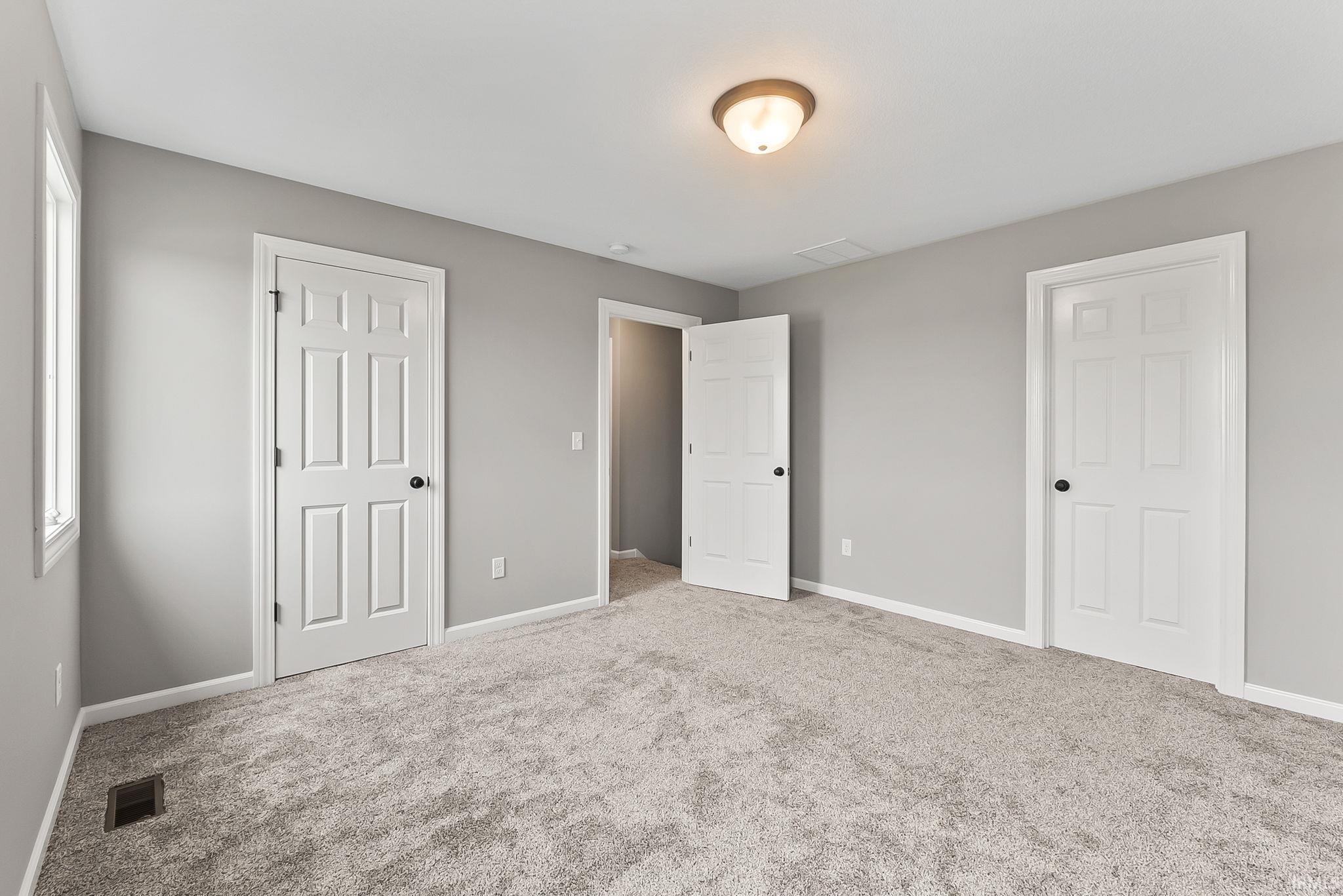Spacious room featuring light gray carpeting, neutral wall paint, and white trim