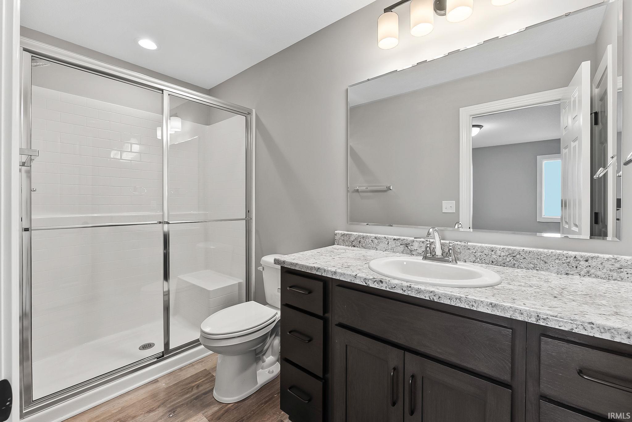 Full bathroom featuring vanity, a shower stall, dark wood-type flooring, and recessed lighting
