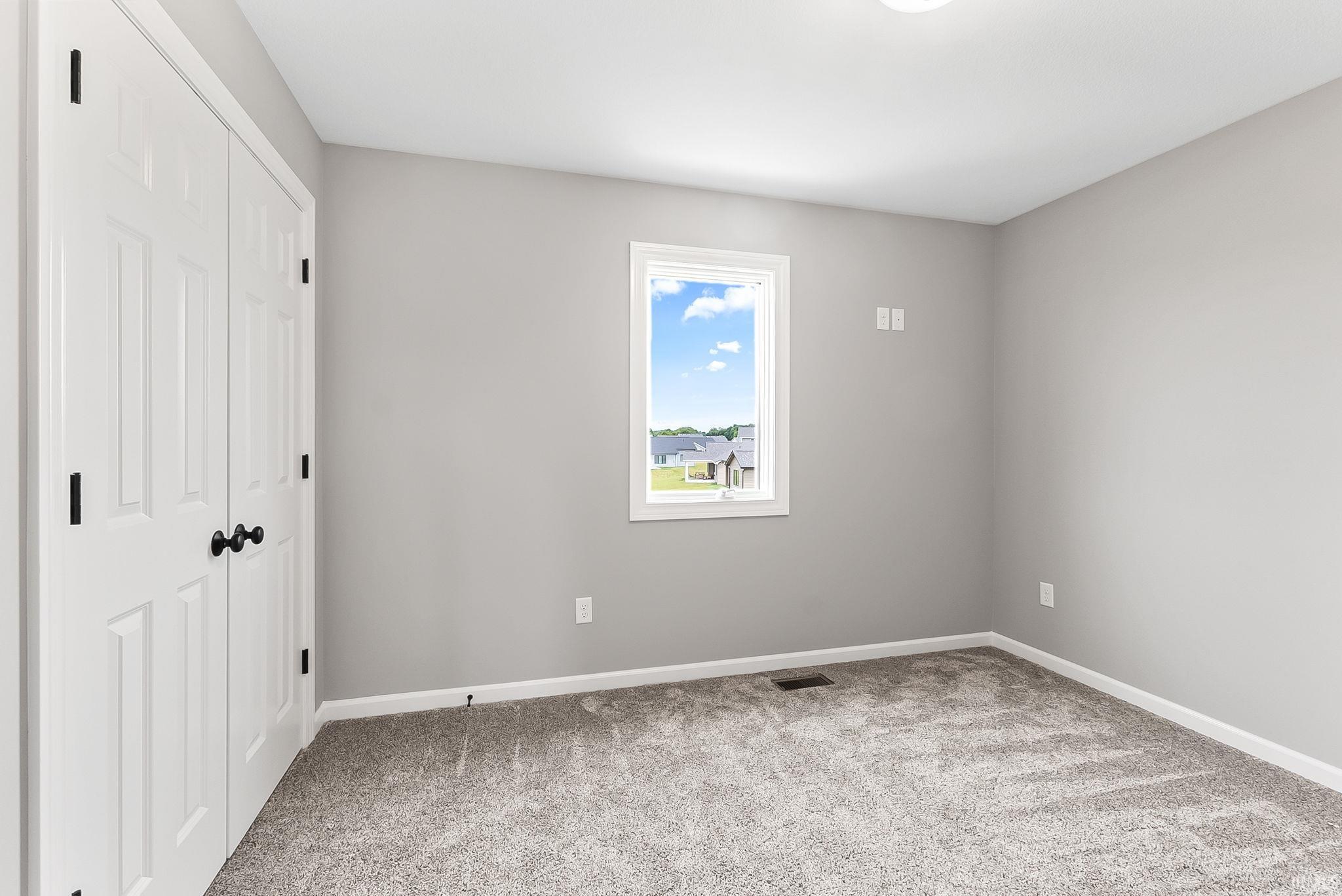 Neutral-toned room featuring a single window, light gray walls, and carpet flooring