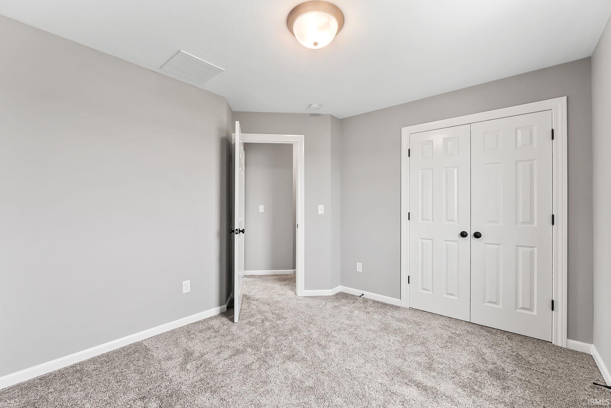 Carpeted room with light grey walls, white trim, and a semi-flush mount ceiling light