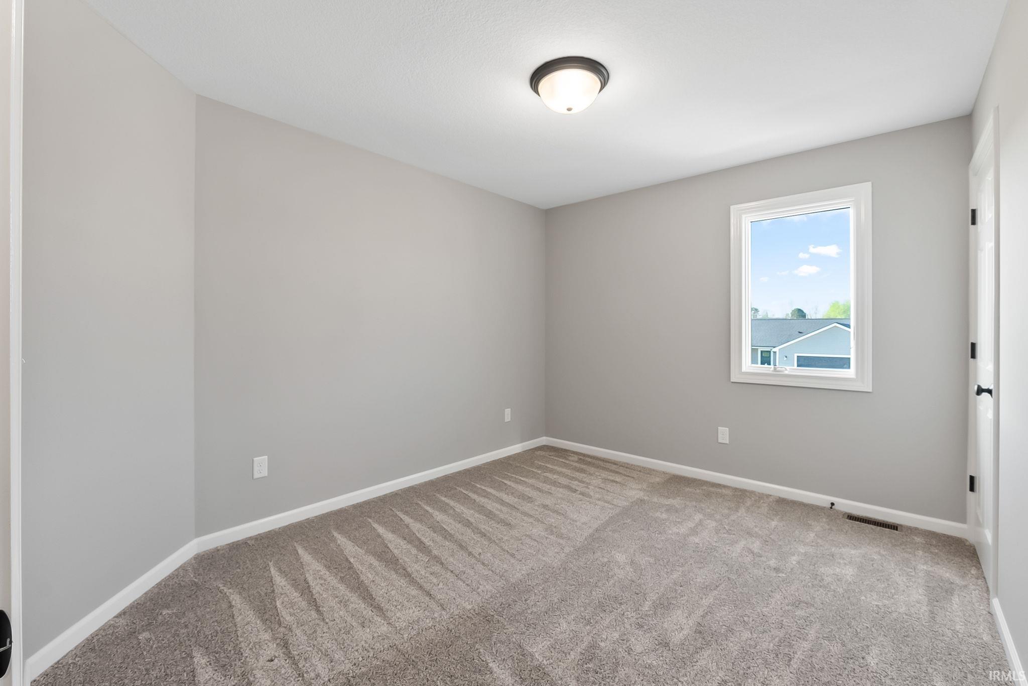 Spare room featuring light carpet and baseboards