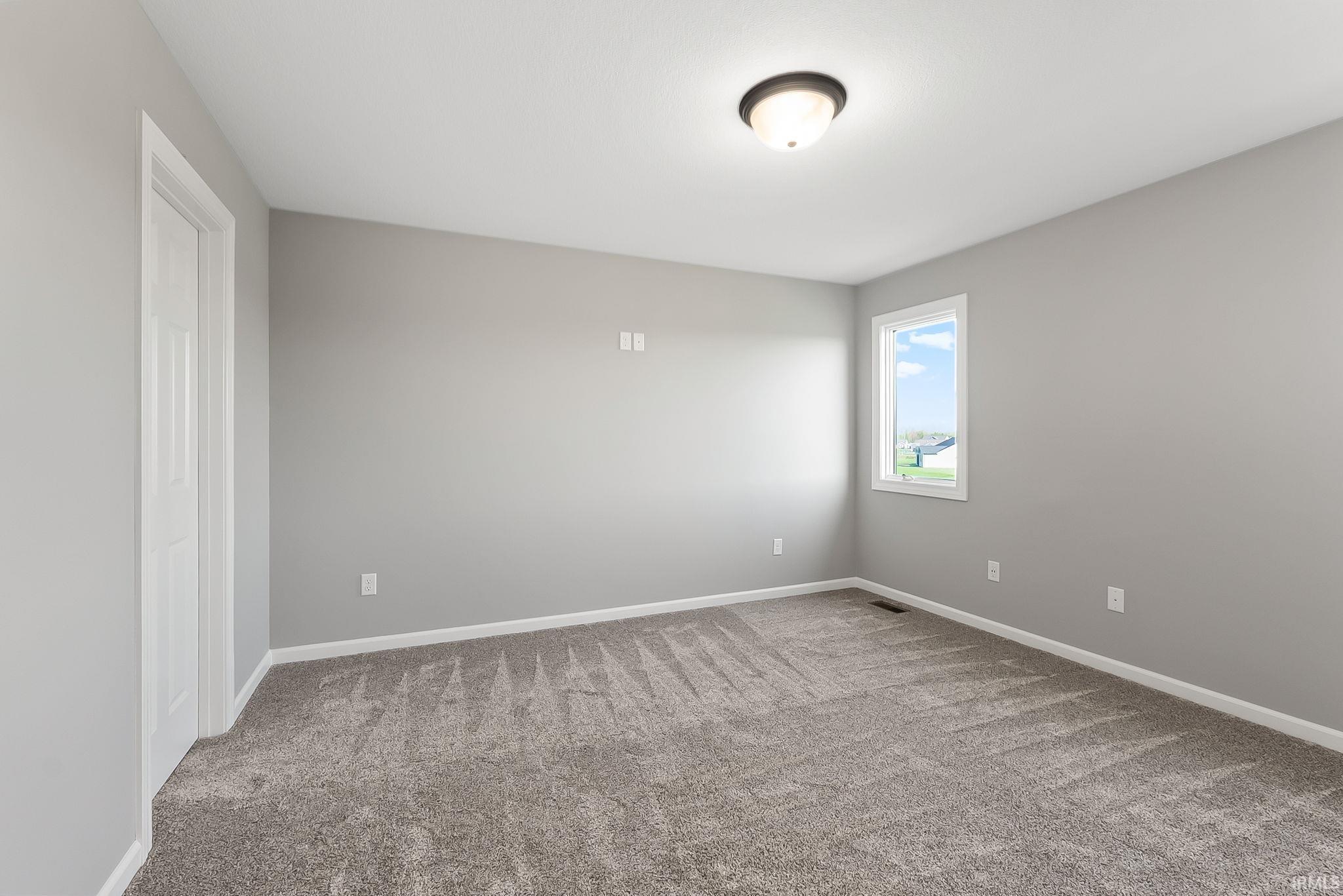 Spare room featuring light colored carpet and baseboards