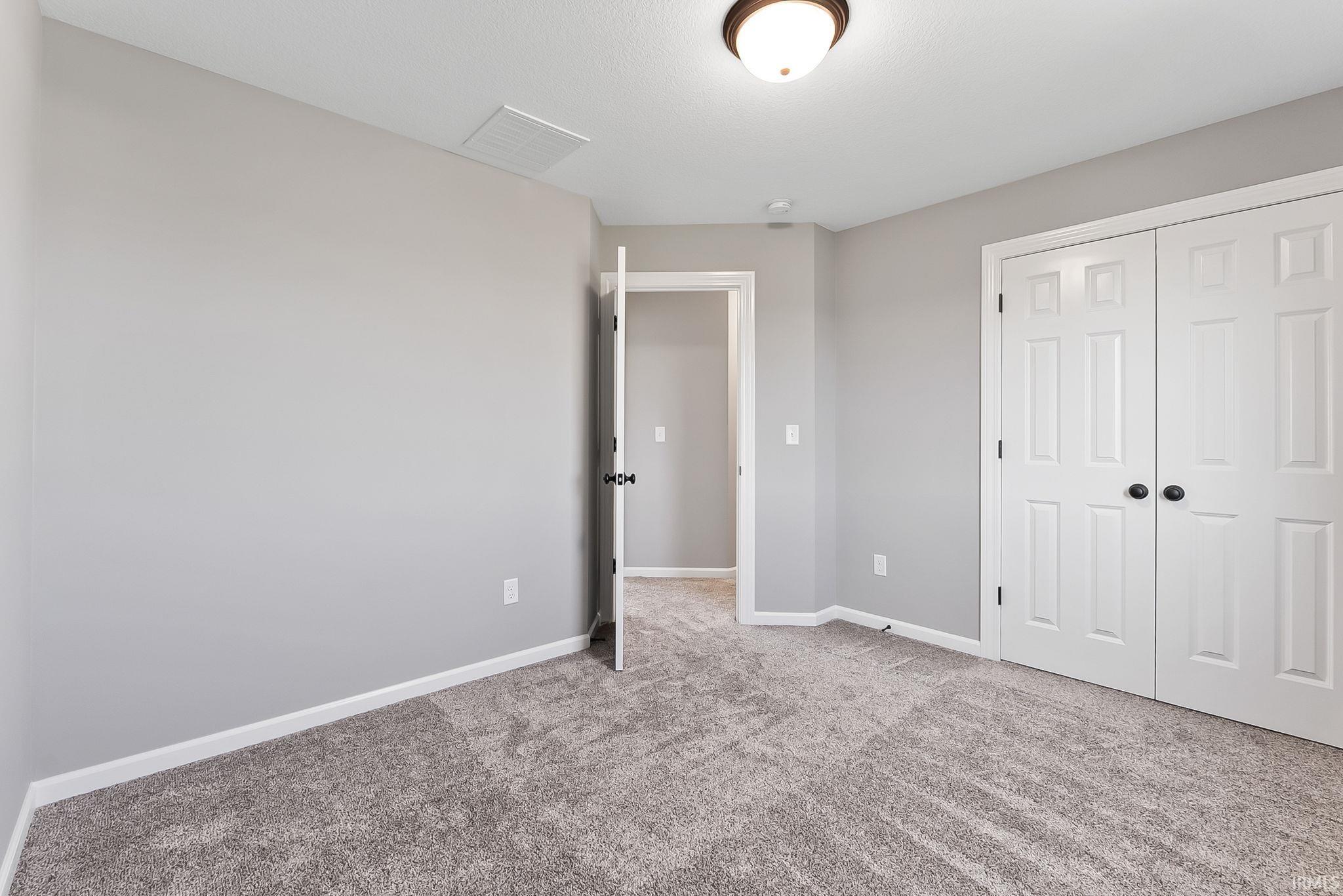 Unfurnished bedroom with light carpet and a closet