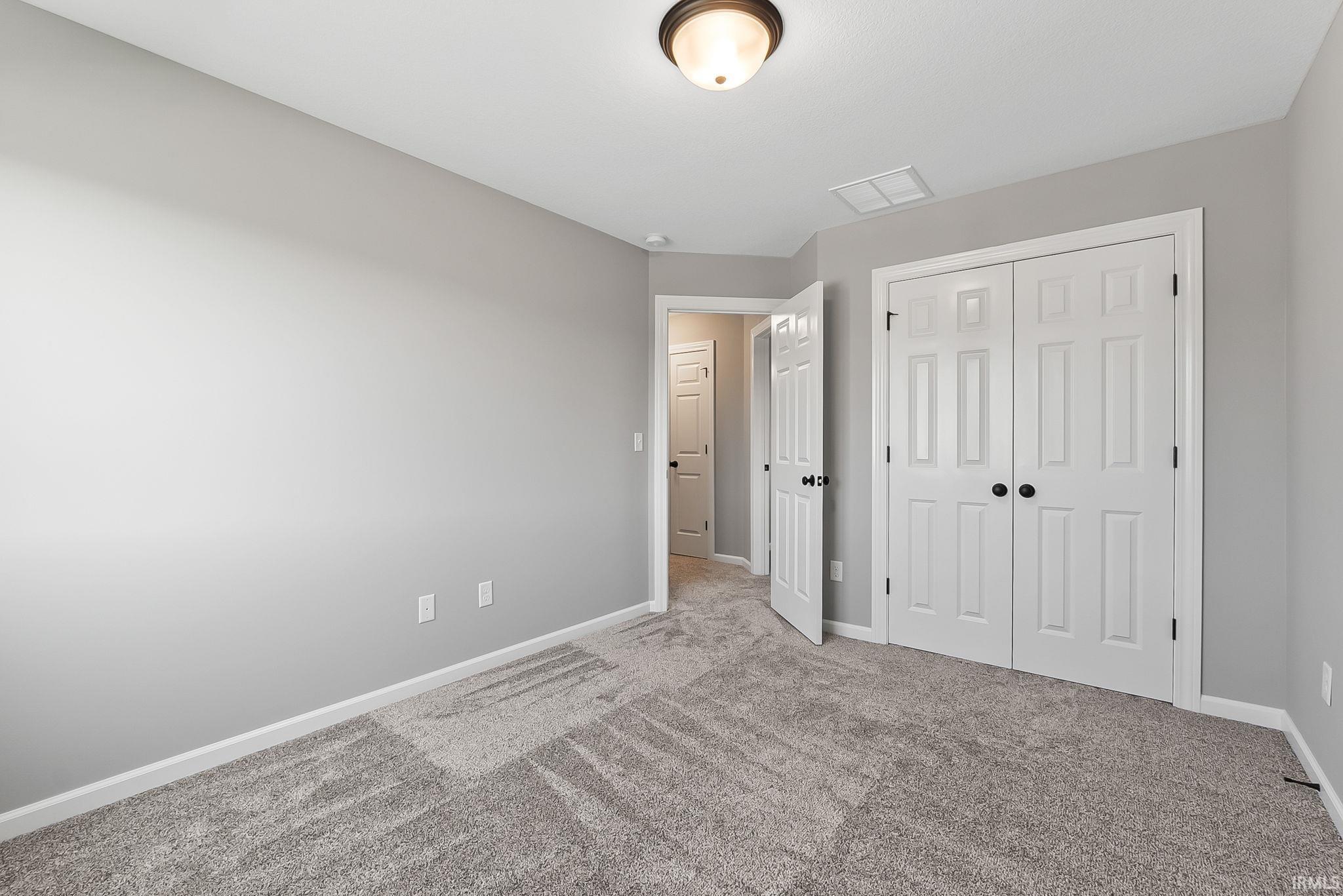 Unfurnished bedroom with light carpet and a closet