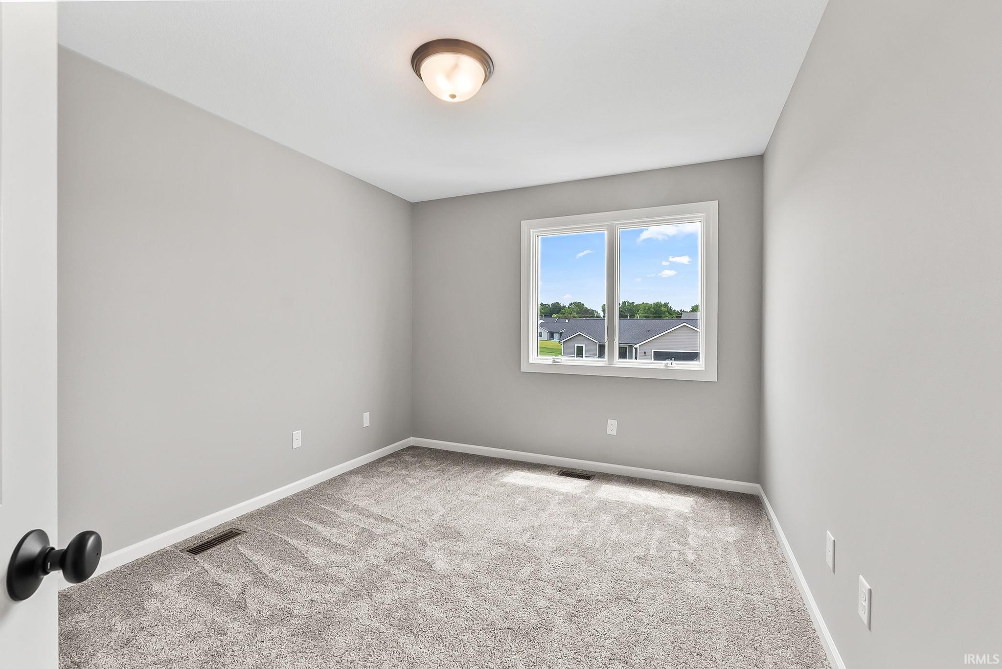 Room with light gray walls, gray carpet, and a white-framed window