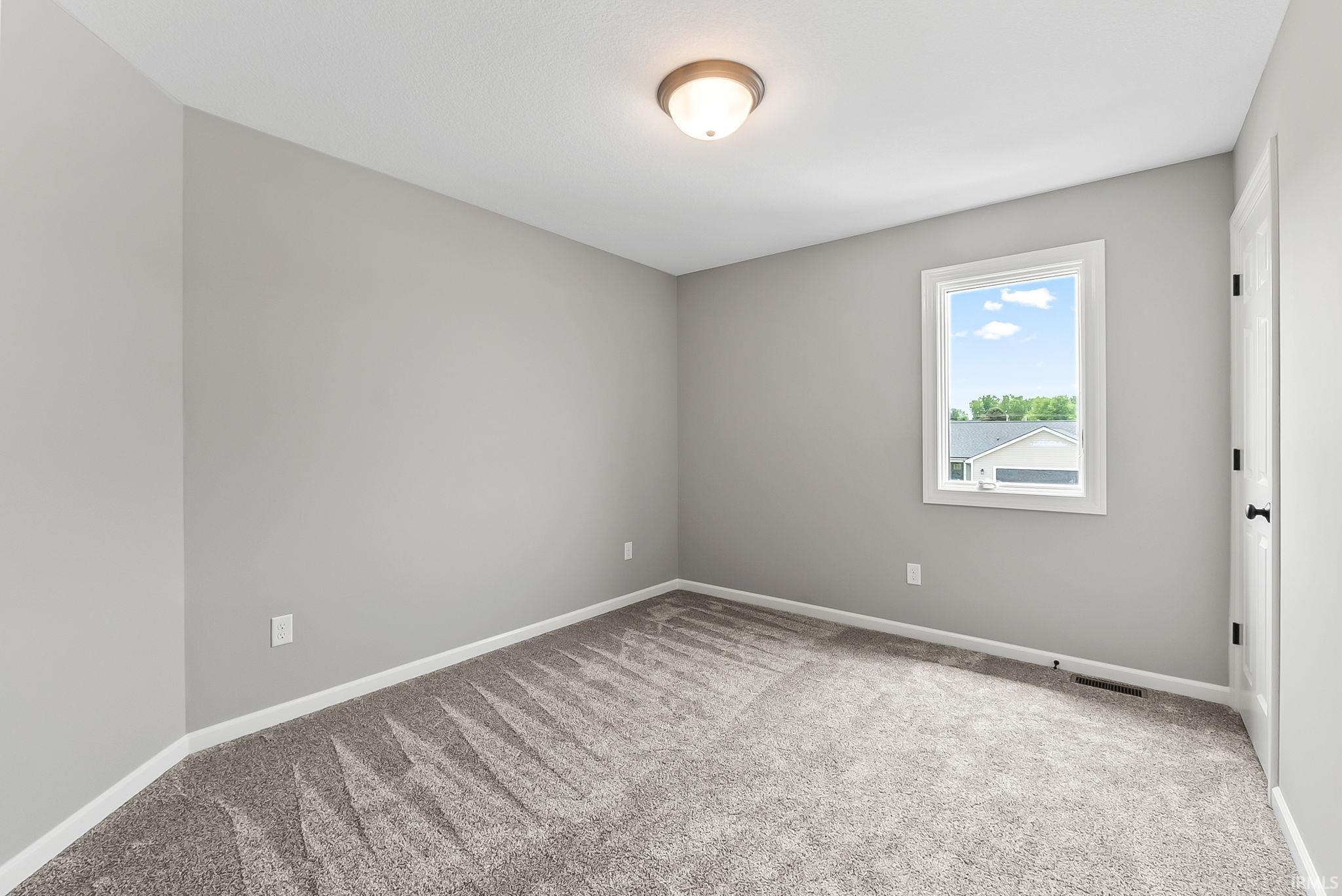 Neutral gray walls with white trim, new gray carpeting, and a white framed window