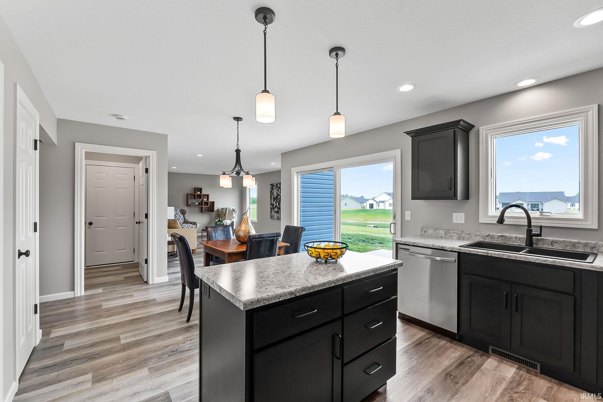 Modern kitchen featuring dark cabinetry, a central island with a light-toned countertop, and stainless steel appliances