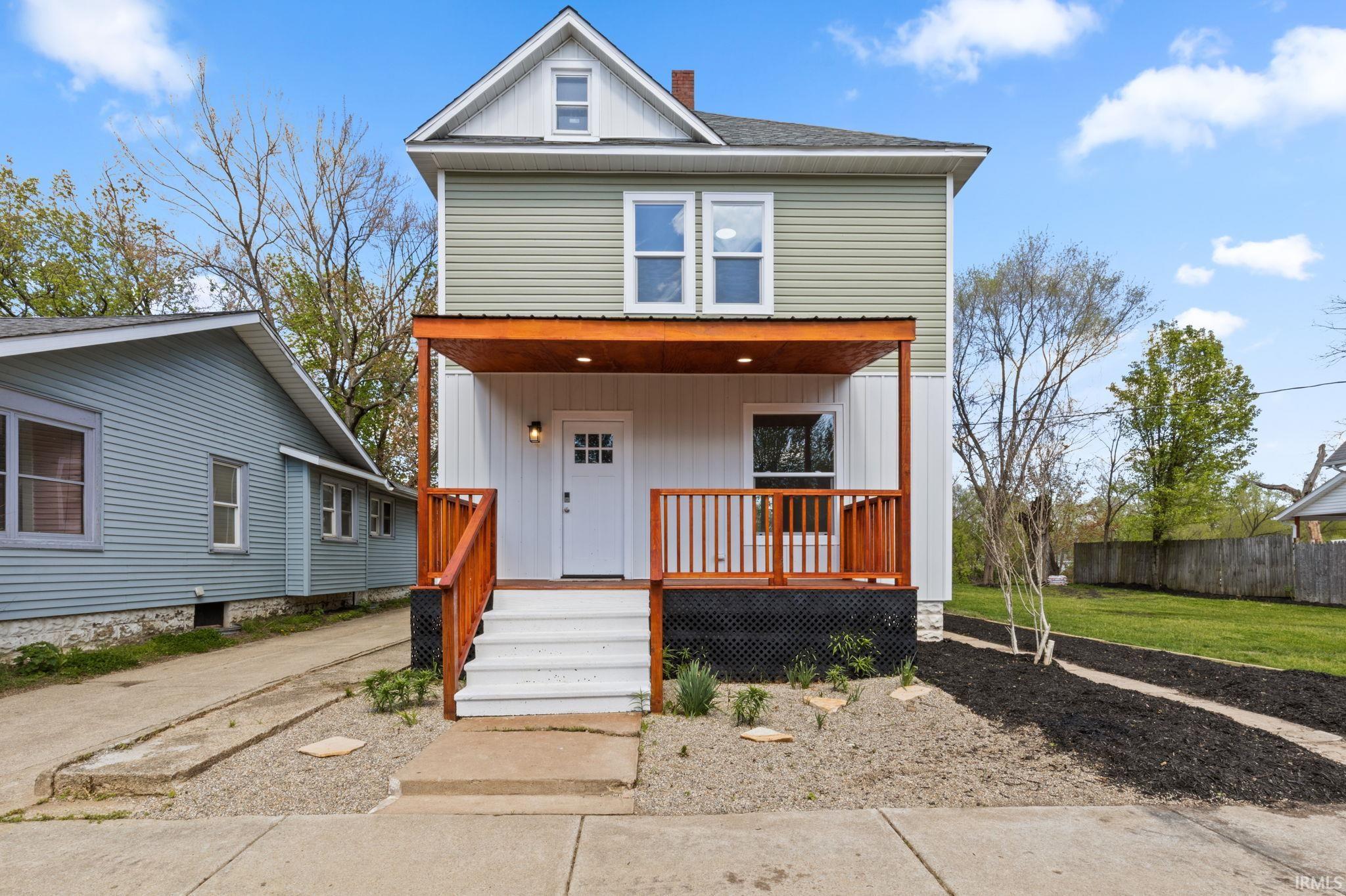 American foursquare style home with covered porch, a chimney, and a front yard