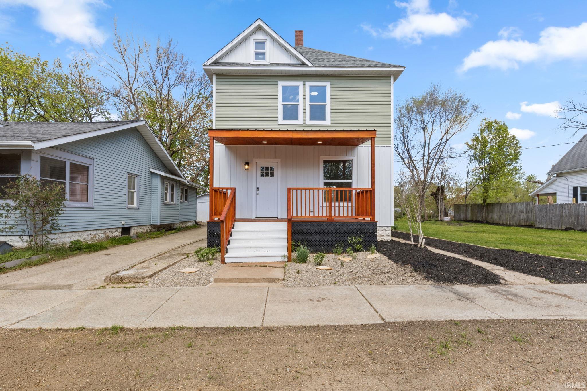 View of front of property with a porch, a chimney, a front yard, and roof with shingles