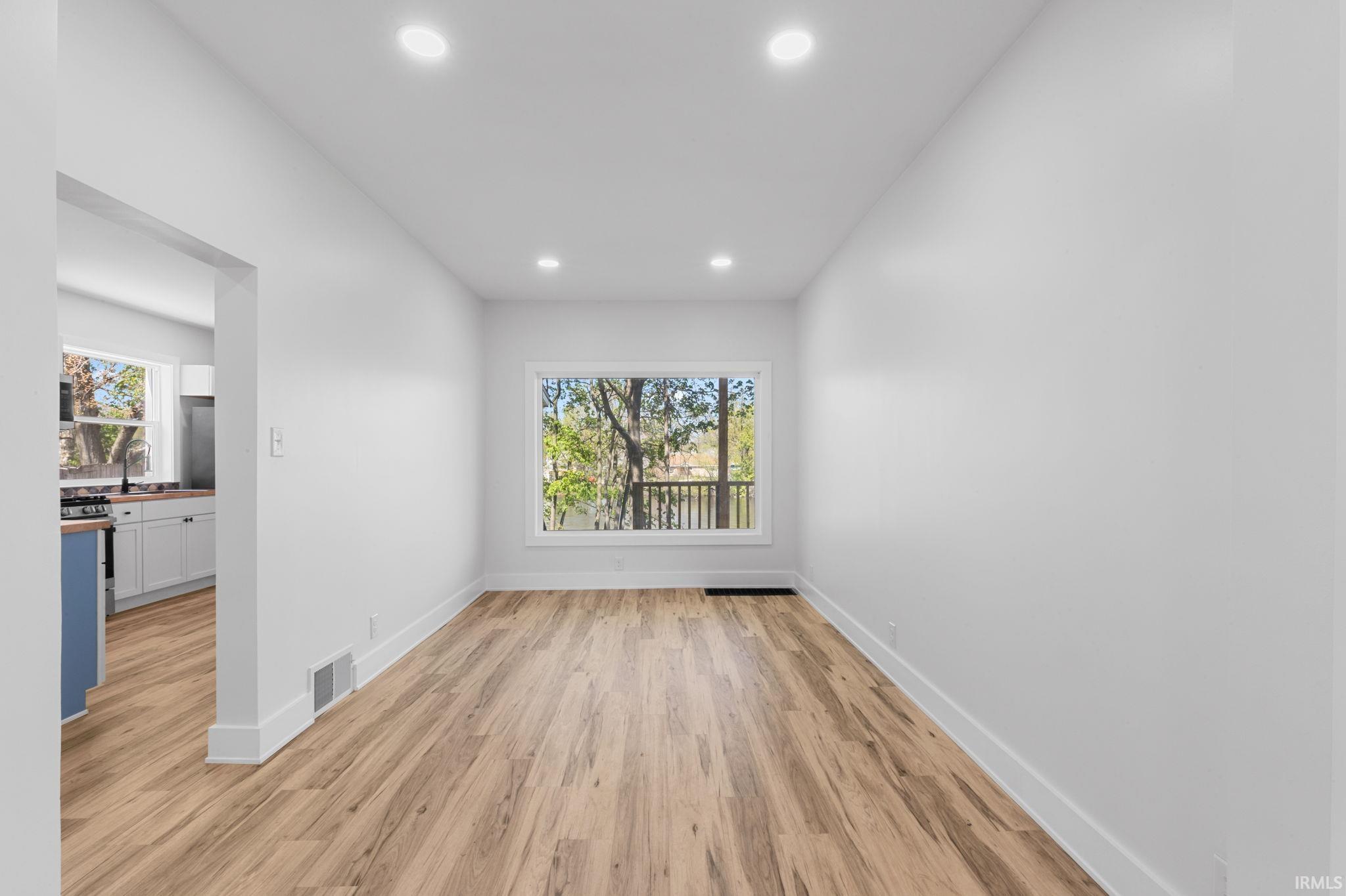 Spare room featuring light wood-style floors, plenty of natural light, and recessed lighting
