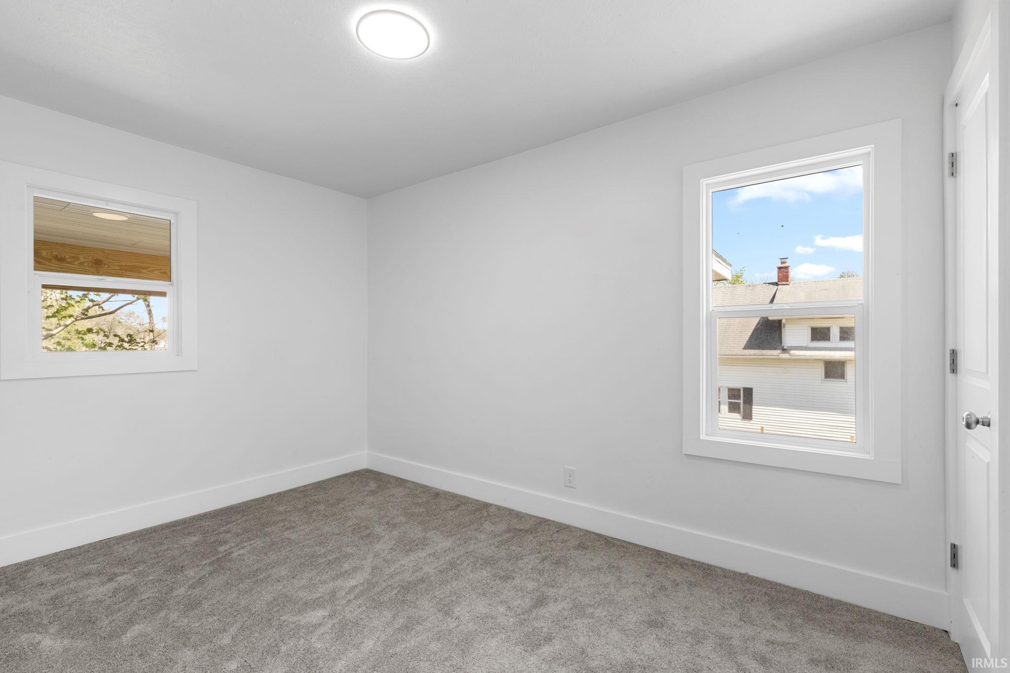 Carpeted spare room featuring baseboards