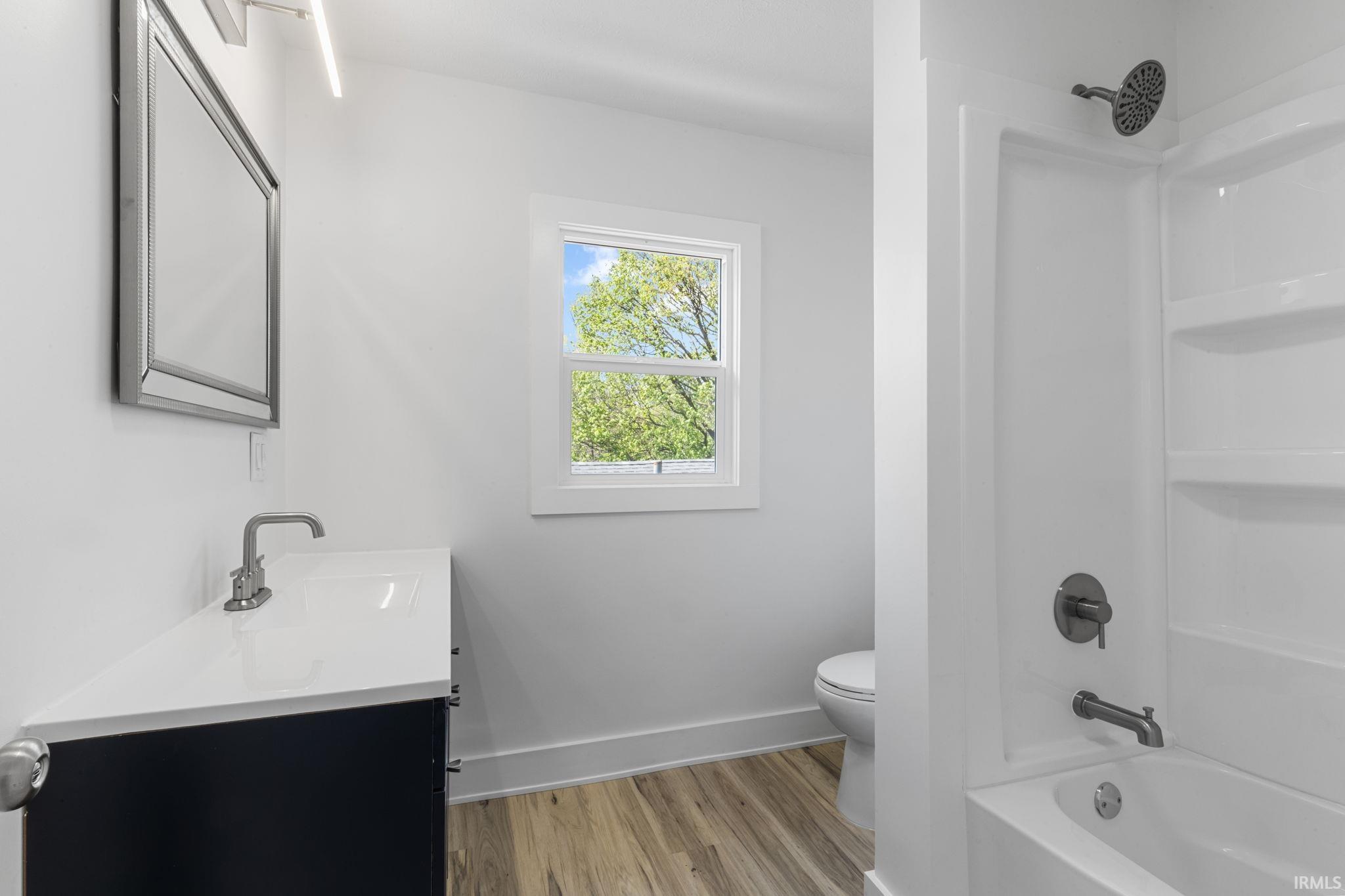 Bathroom with vanity, light wood-style flooring, and shower / tub combination
