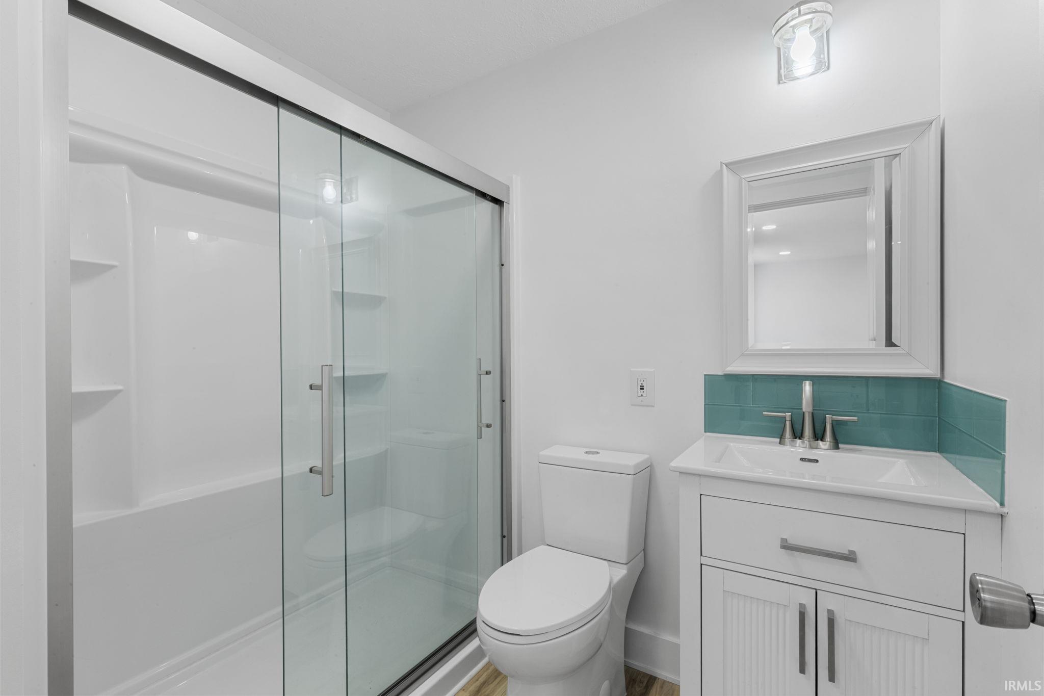Bathroom with vanity, a stall shower, and decorative backsplash