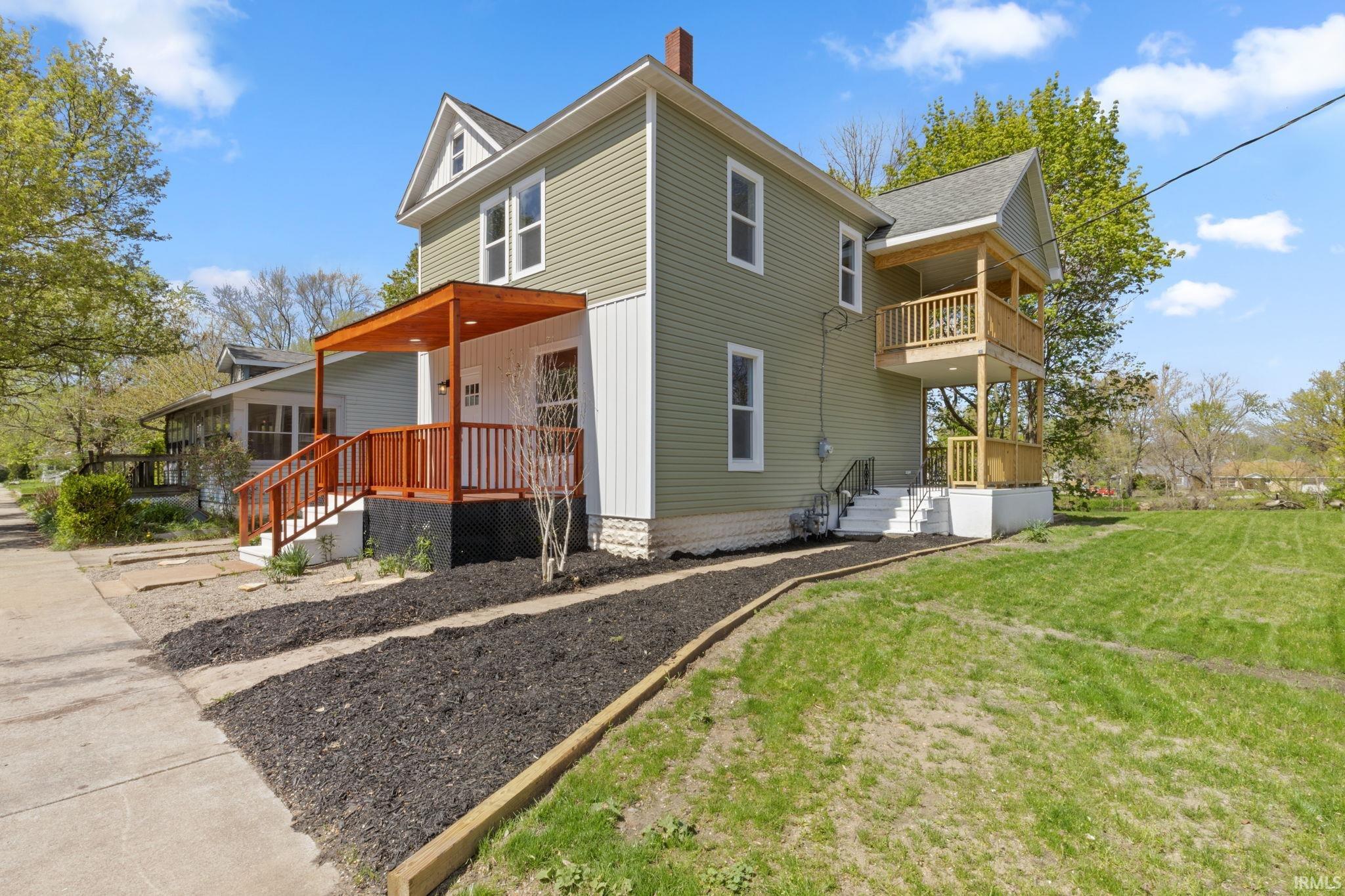 View of home's exterior with a porch, a chimney, and a yard
