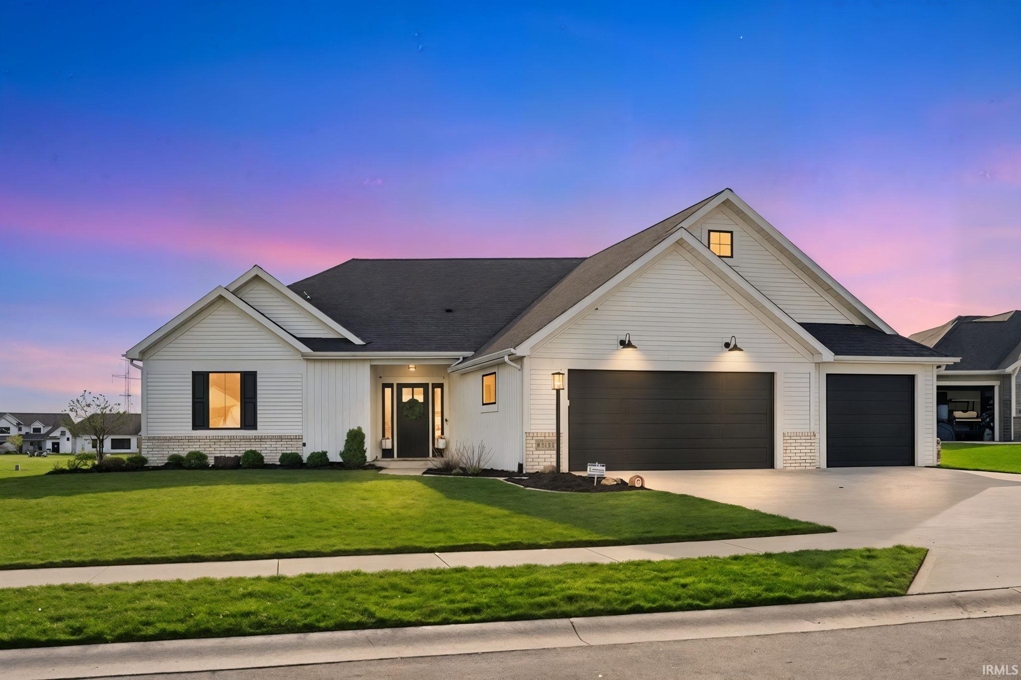 View of front facade featuring brick siding, concrete driveway, an attached garage, and a front lawn