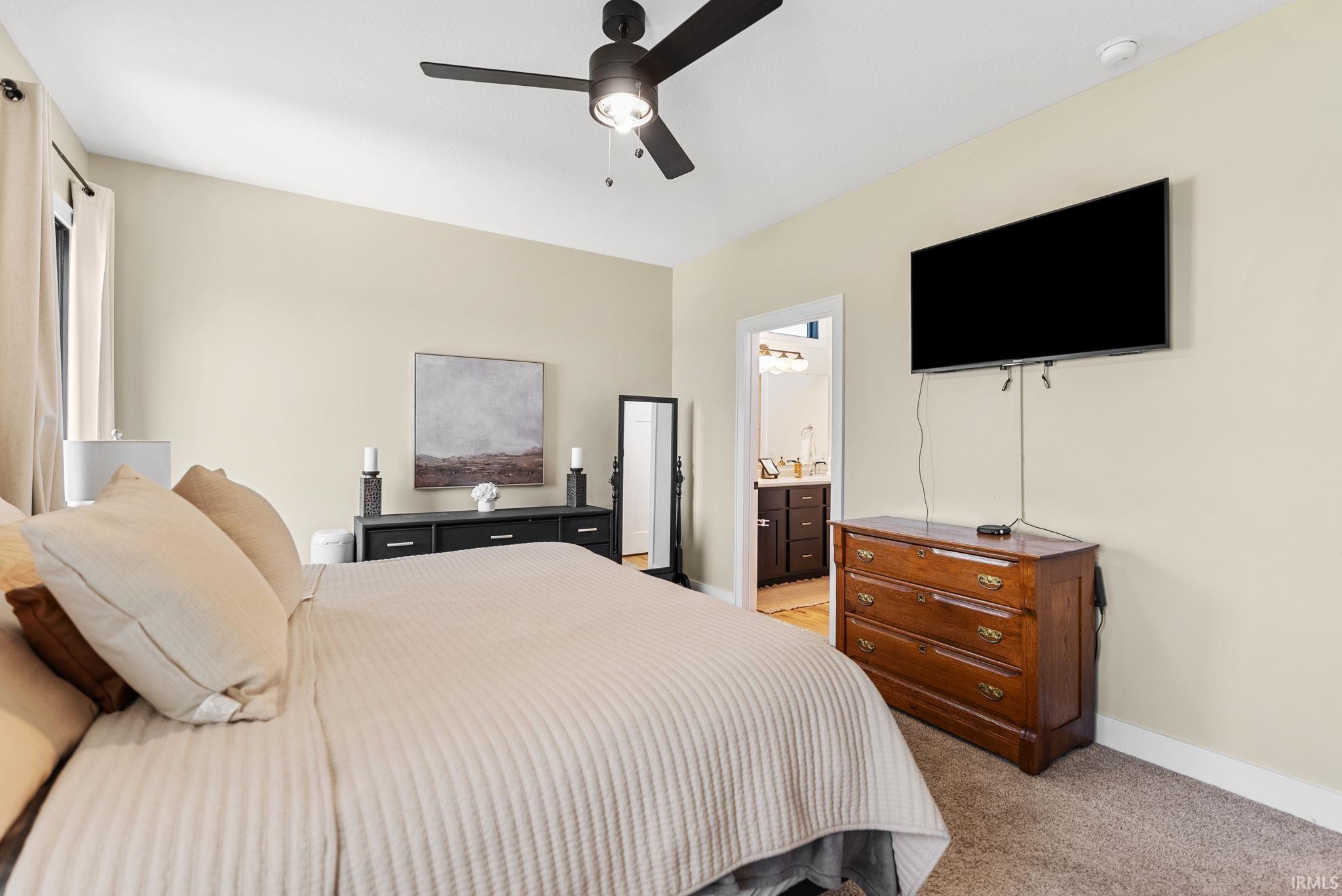 Carpeted room with a ceiling fan, light-toned walls, and a window with a curtain