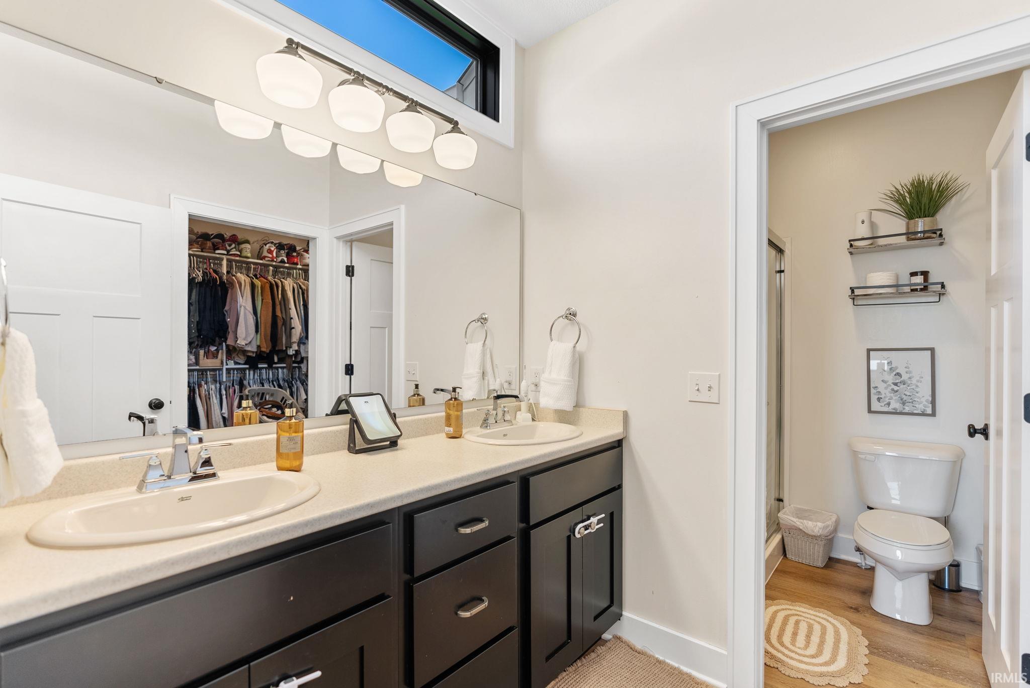 Dual vanity with light-toned countertop, two integrated sinks, dark wood-finish cabinetry, and chrome fixtures