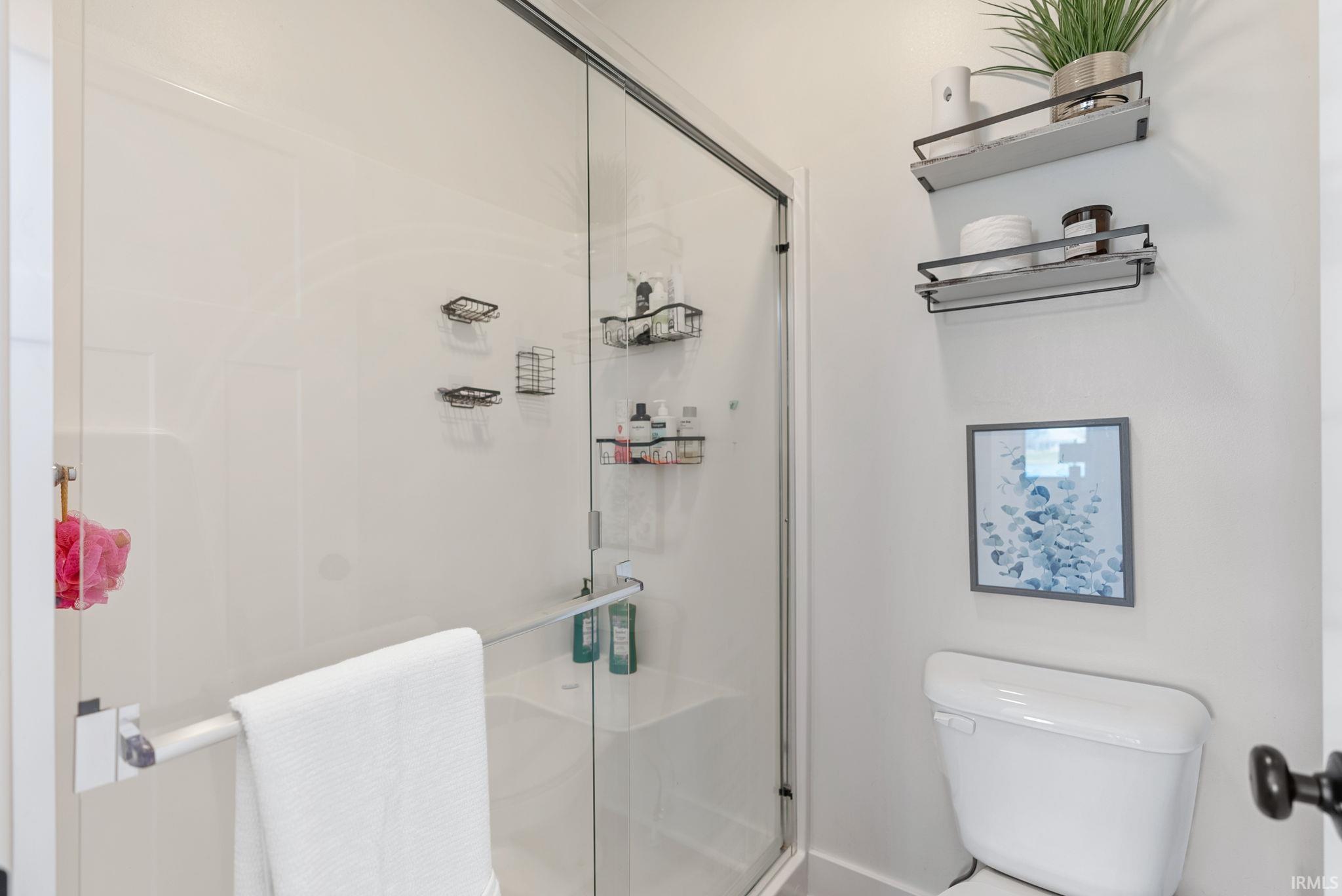 Glass-enclosed shower with white paneling and a built-in bench