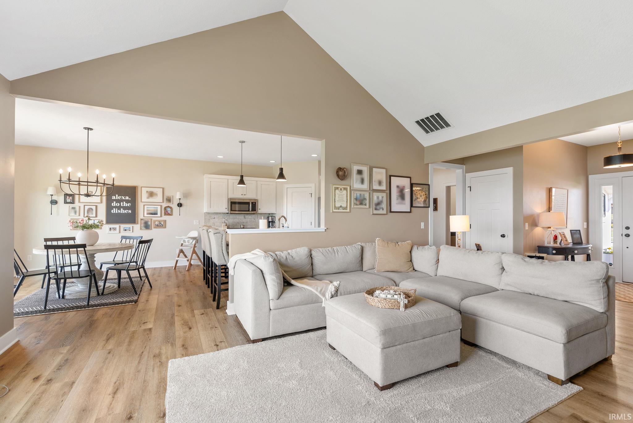 Vaulted ceiling living area featuring wood-finish flooring, an open concept layout, and recessed lighting