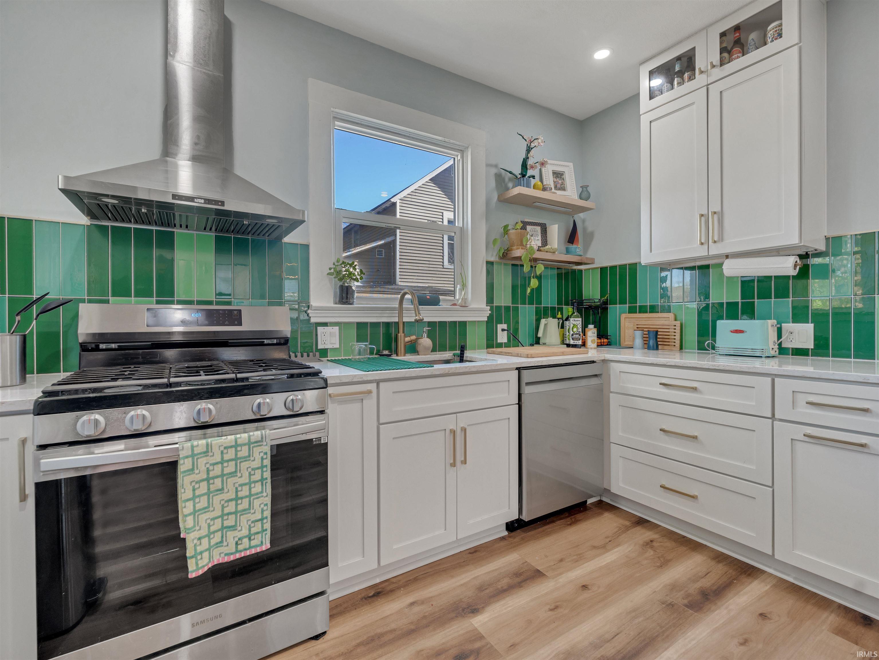 Kitchen with stainless steel appliances, white cabinetry, light wood-style flooring, glass fronted cabinets, and open shelves