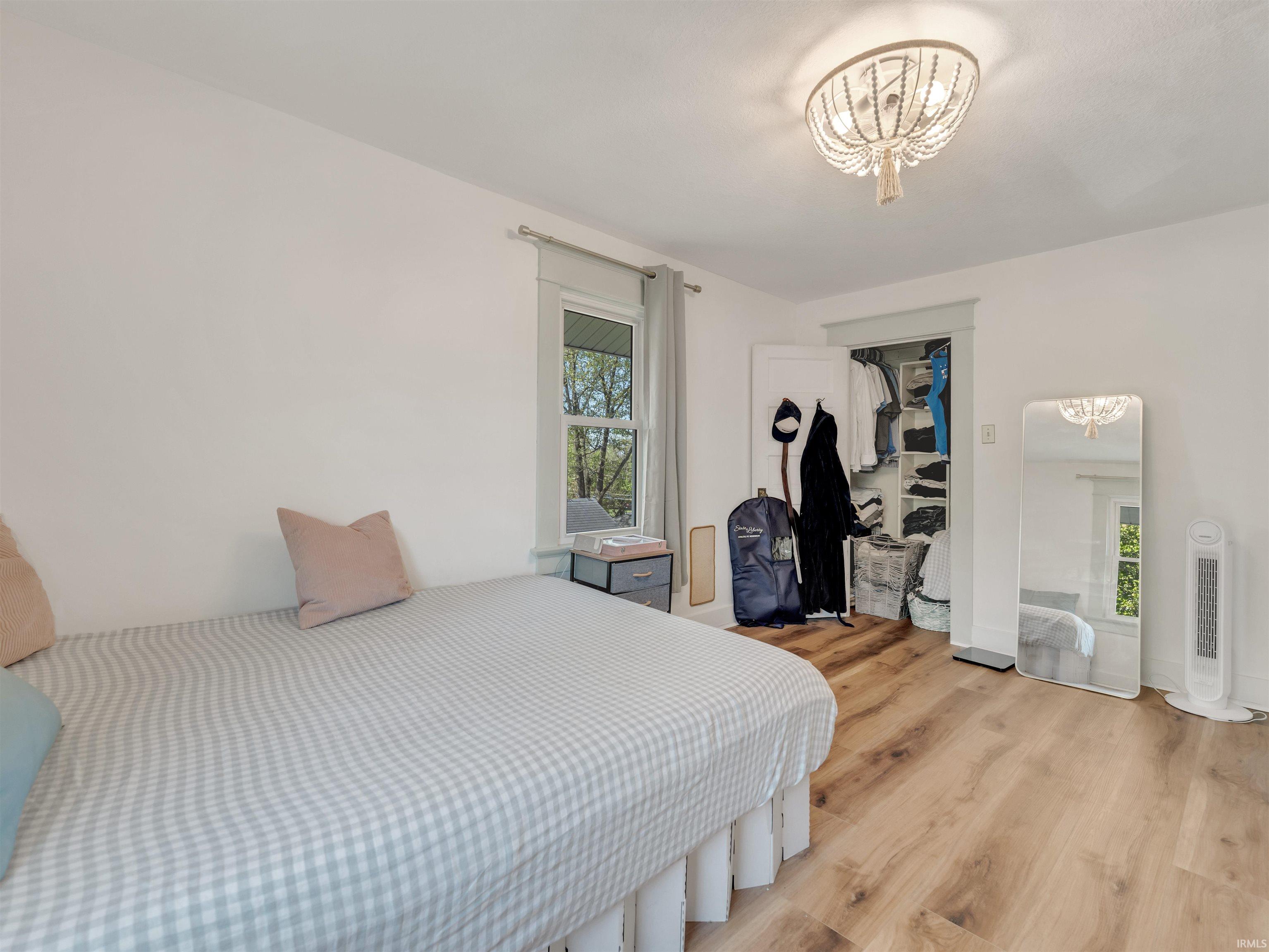 Bedroom featuring wood finished floors, suspended lighting, and a closet