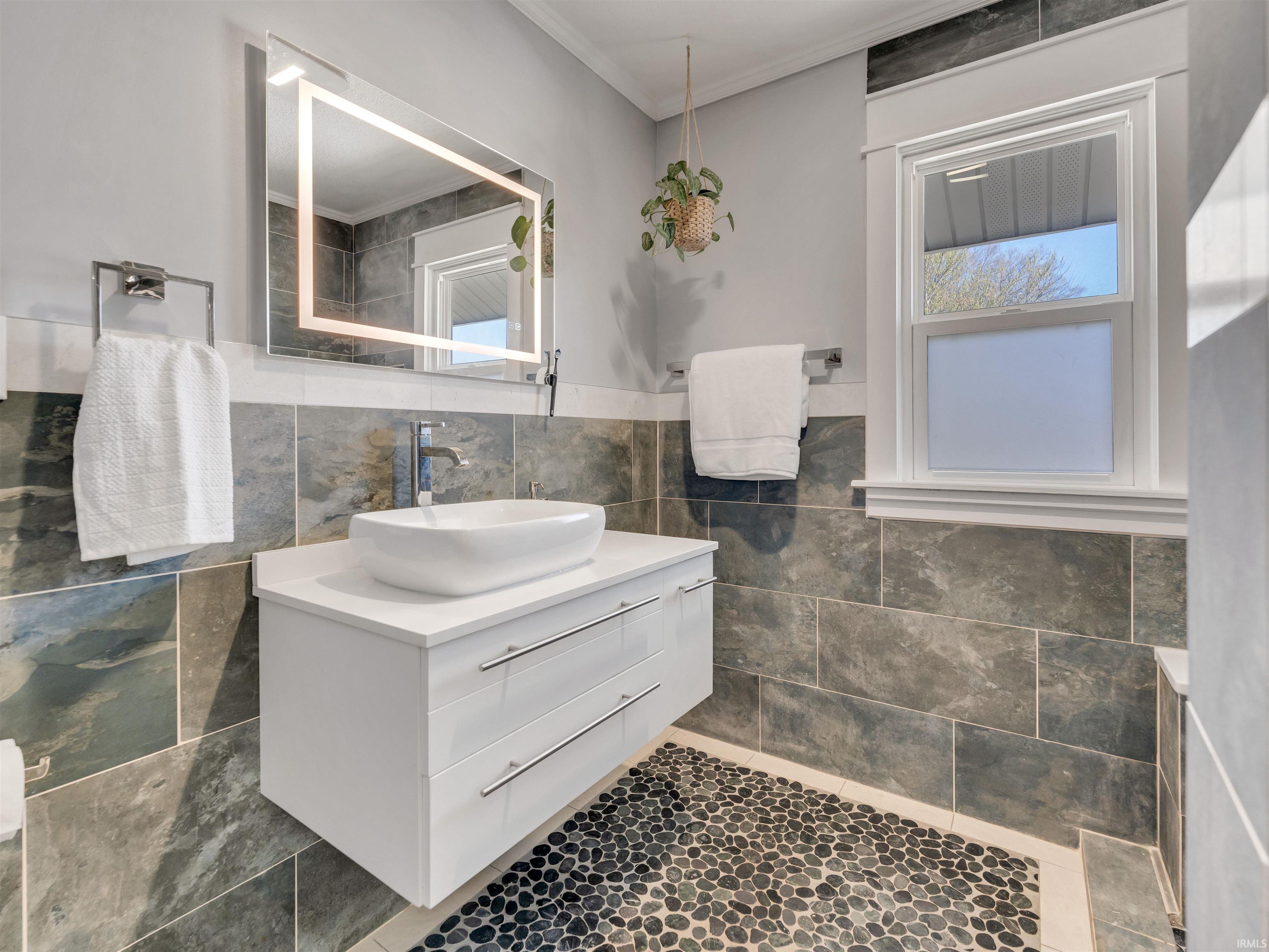 Bathroom with vanity, tile walls, wainscoting, and crown molding