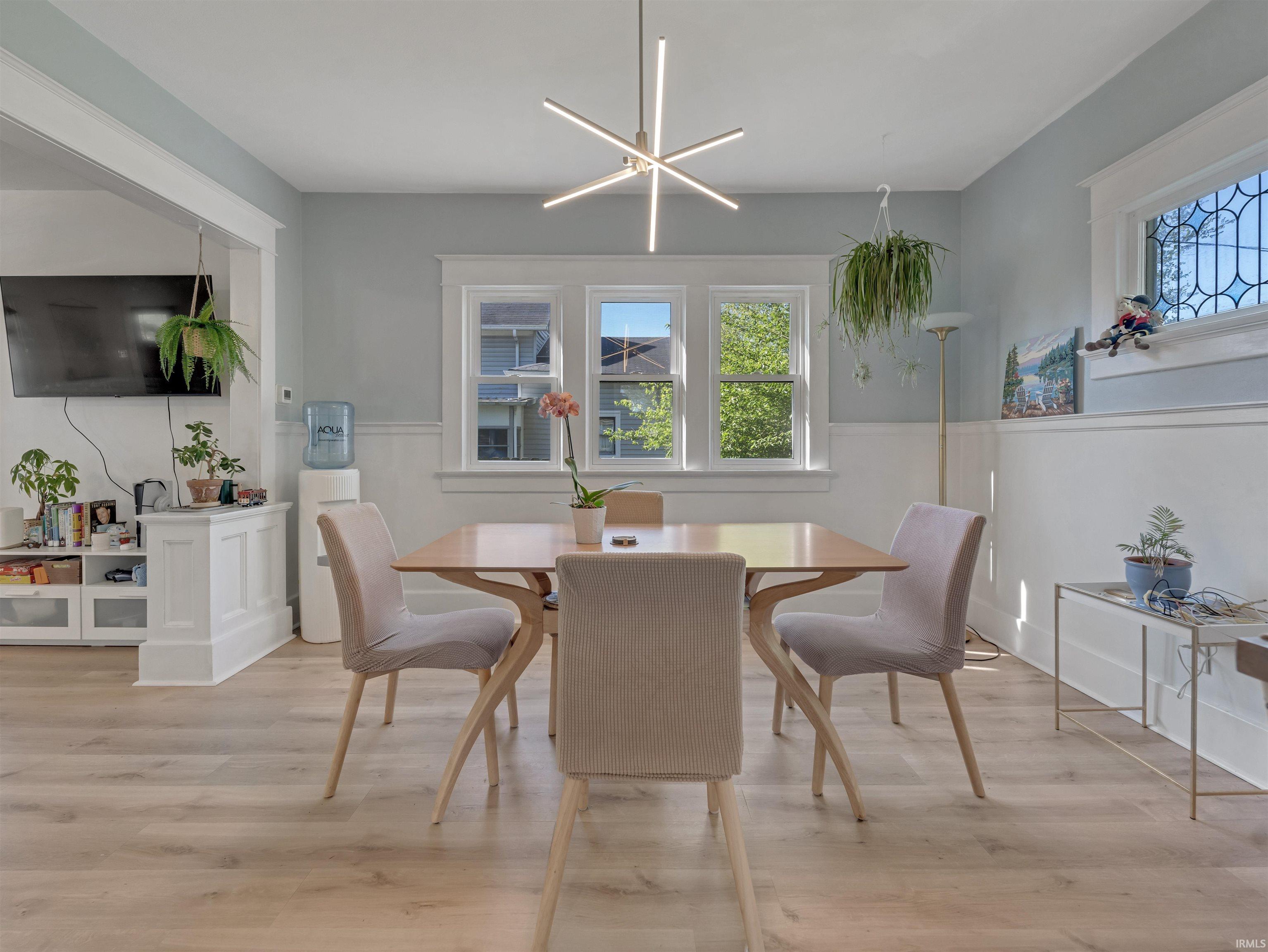 Dining room with light wood-style flooring and a wainscoted wall