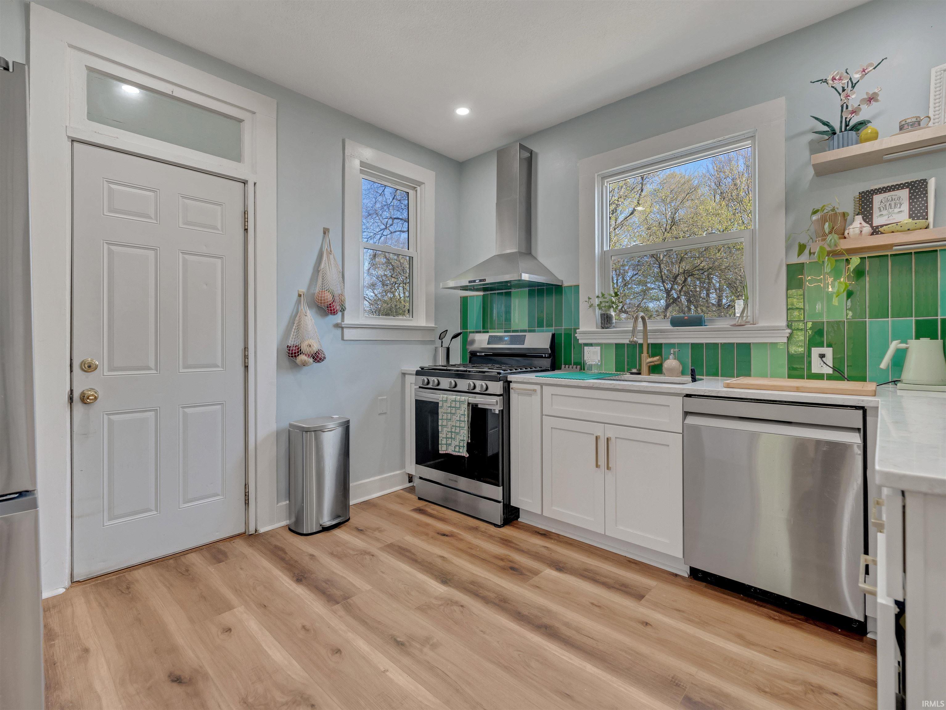 Kitchen featuring stainless steel appliances, white cabinetry, open shelves, light wood-type flooring, and light stone counters