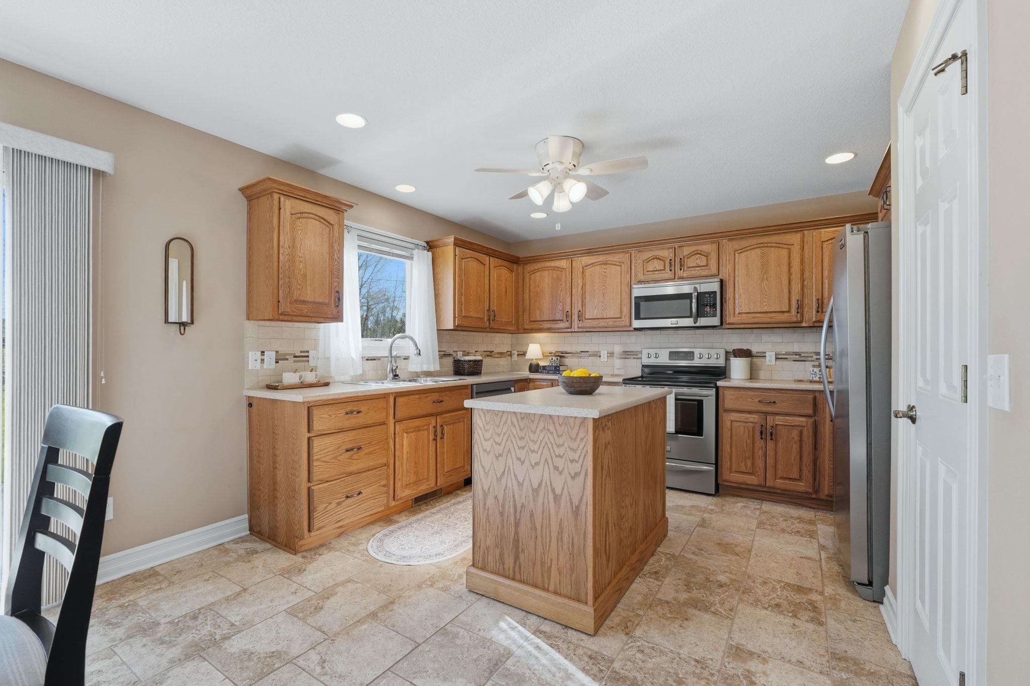 Kitchen with backsplash, wood finish cabinetry, stainless steel appliances, light countertops, and recessed lighting