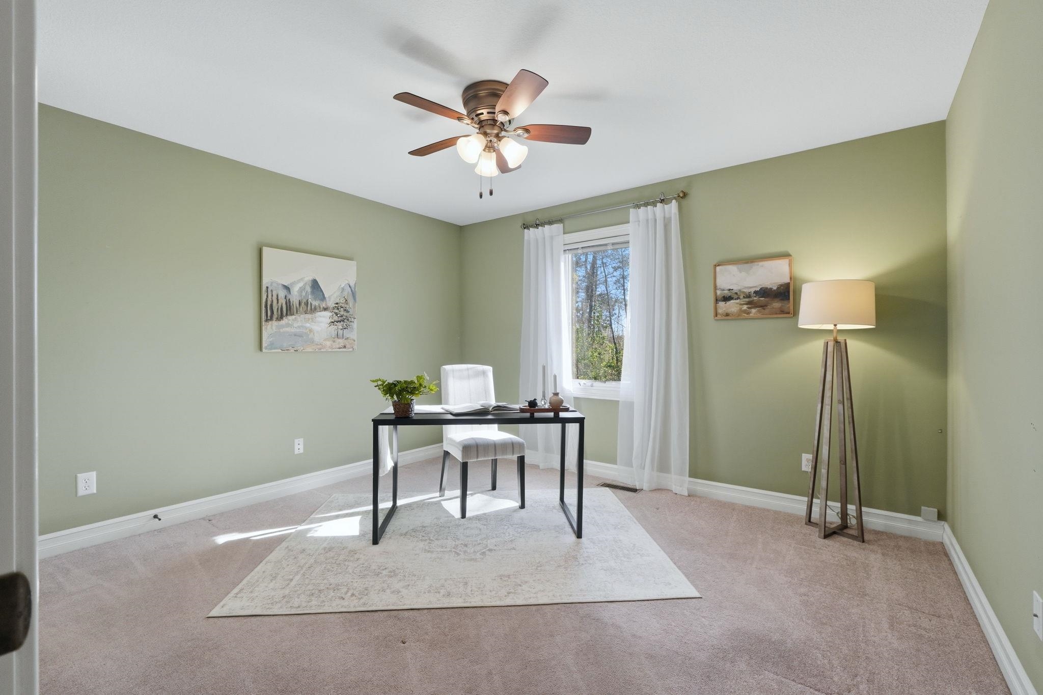 Home office with light carpet and a ceiling fan