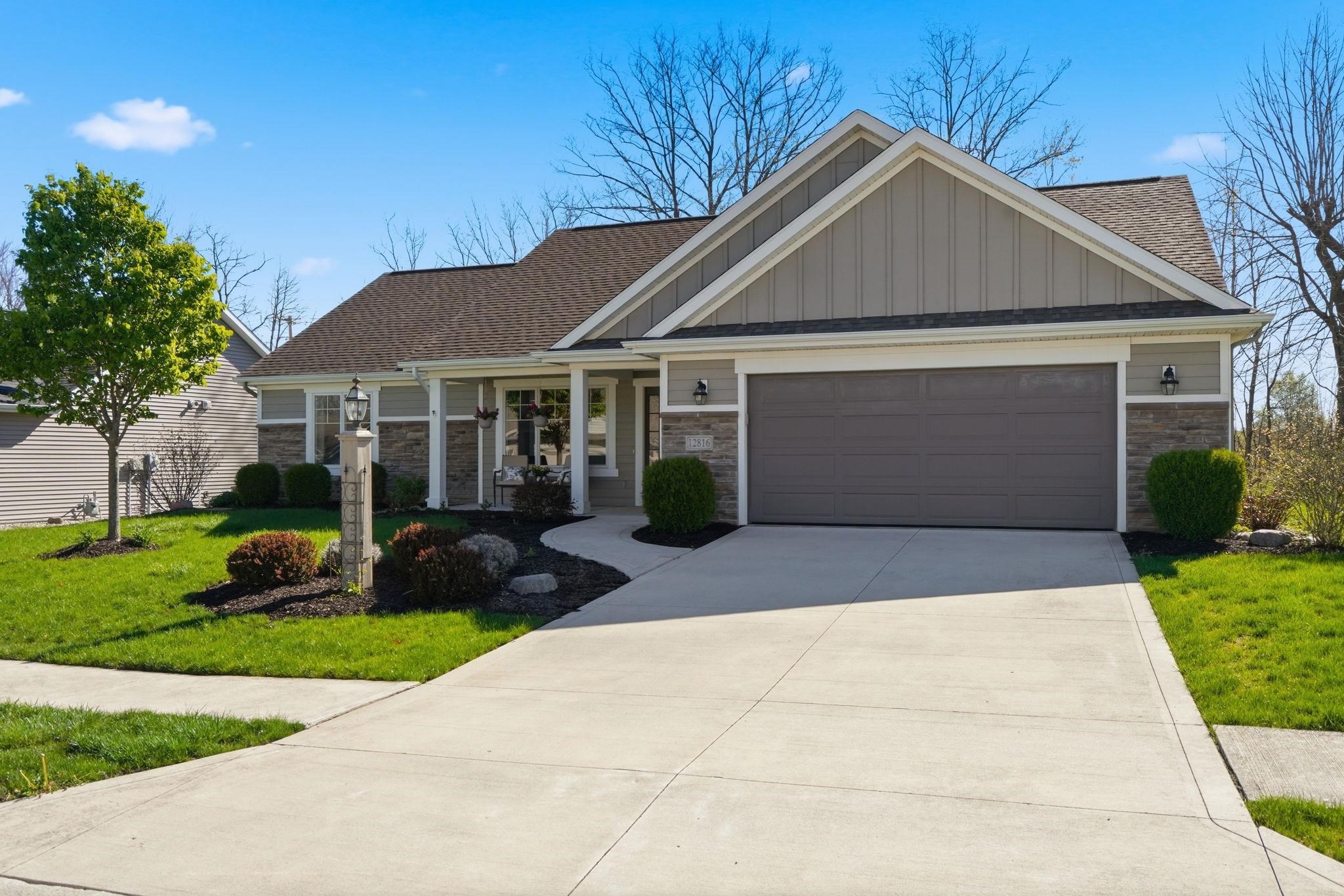 View of front of property featuring board and batten siding, a front lawn, a porch, a garage, and driveway