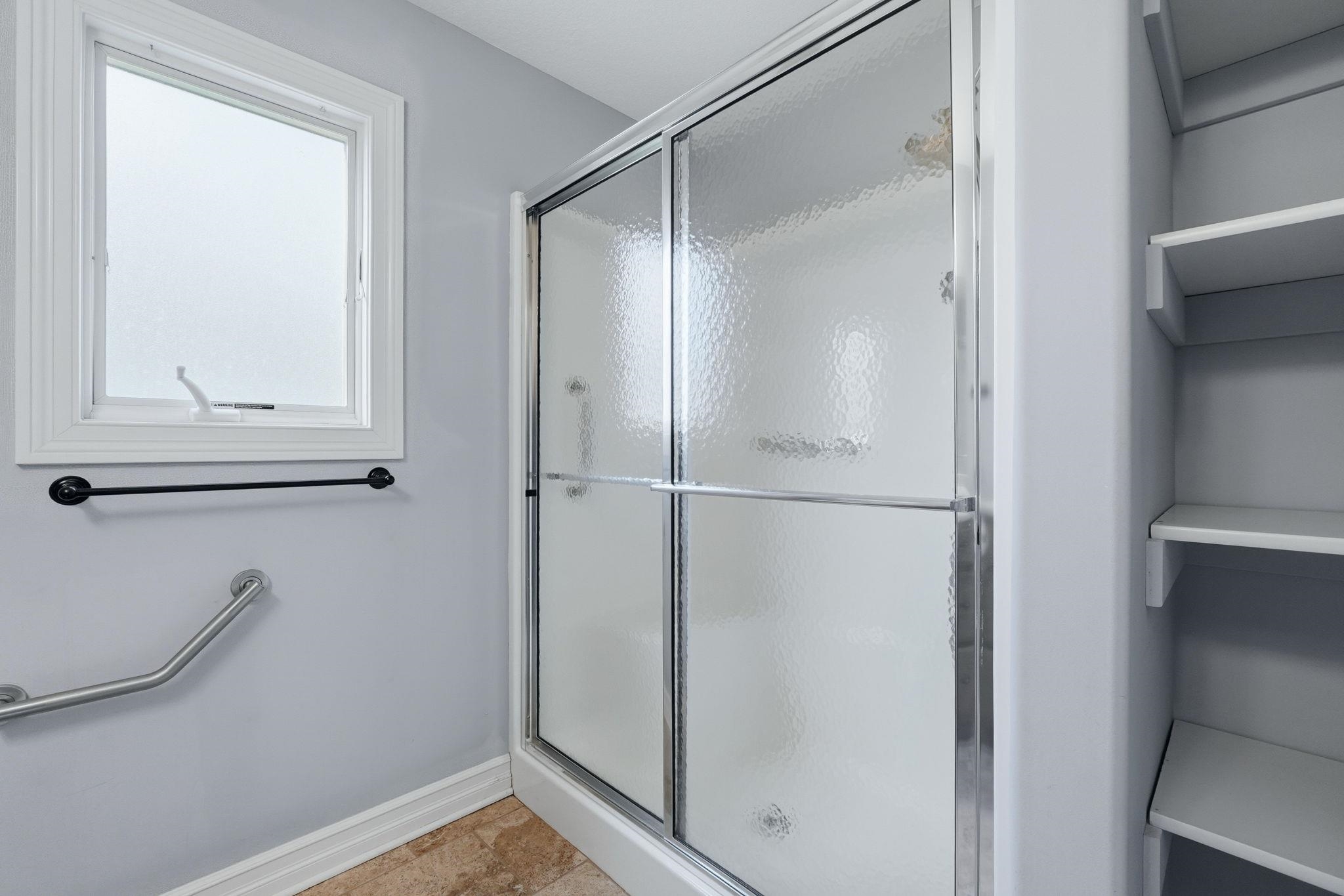 Full bath featuring a shower stall and baseboards