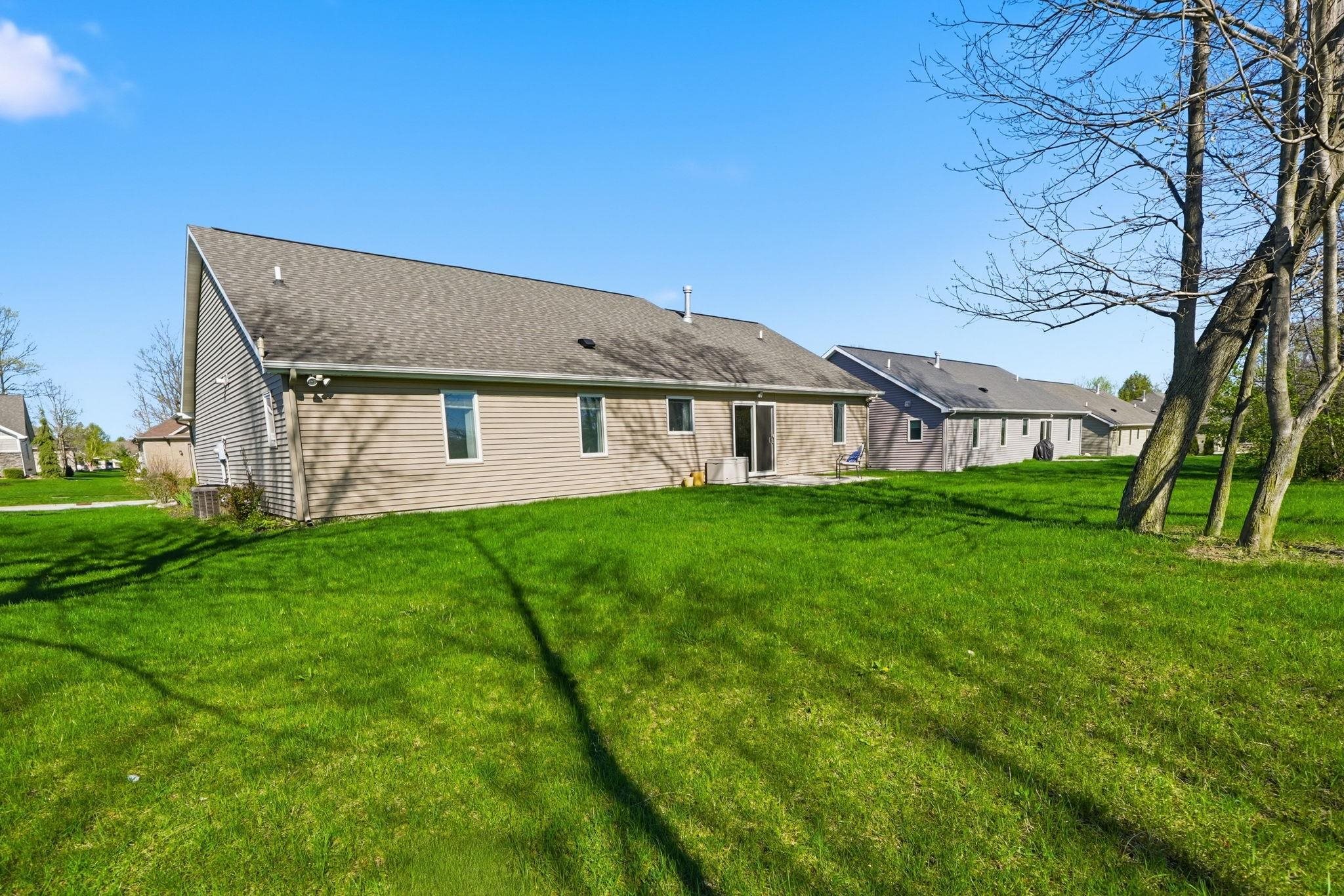 Rear view of house featuring a lawn, a patio, and a shingled roof