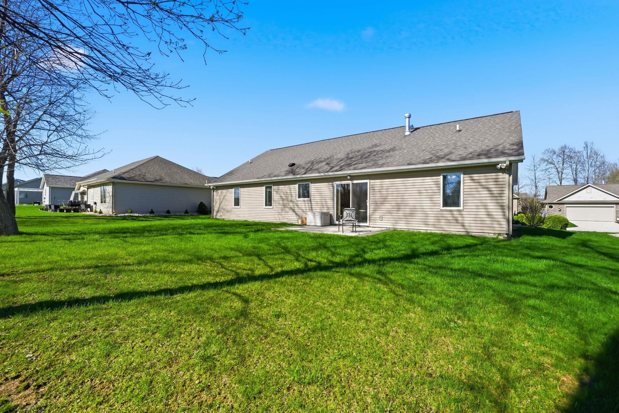 Rear view of house featuring a patio and a lawn