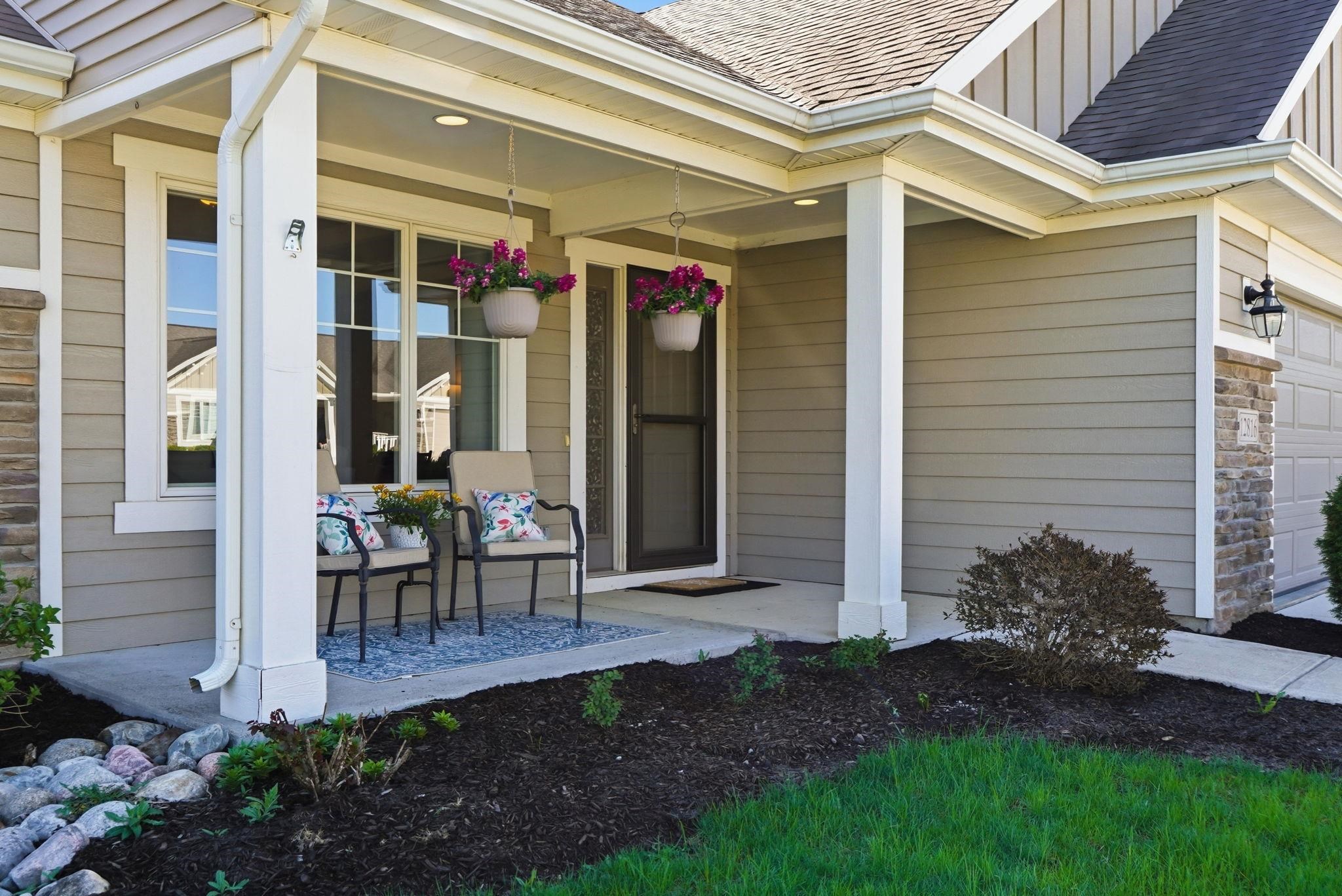 View of exterior entry with roof with shingles, covered porch, board and batten siding, and stone siding
