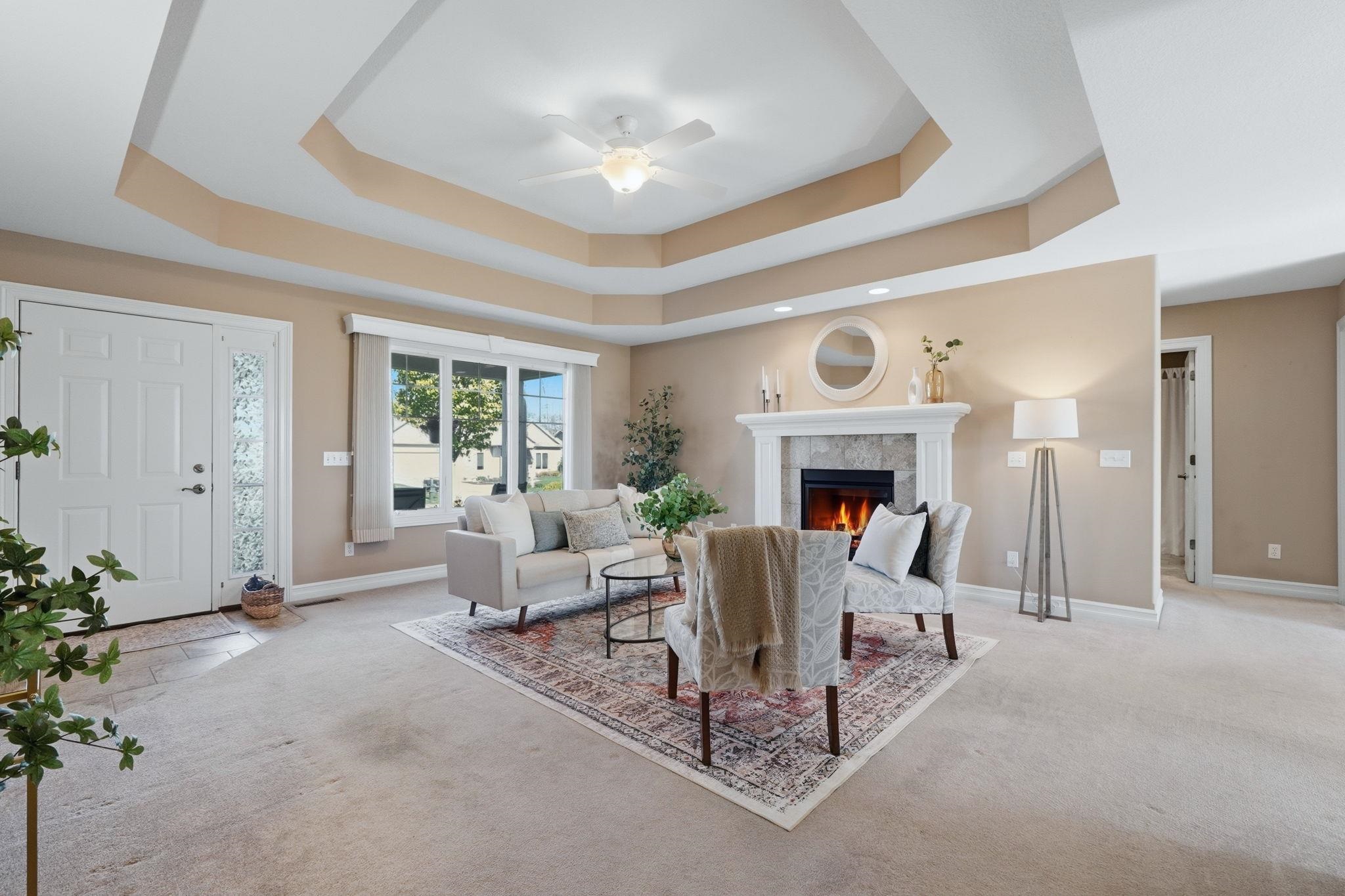 Living area with ceiling fan, light colored carpet, and a fireplace