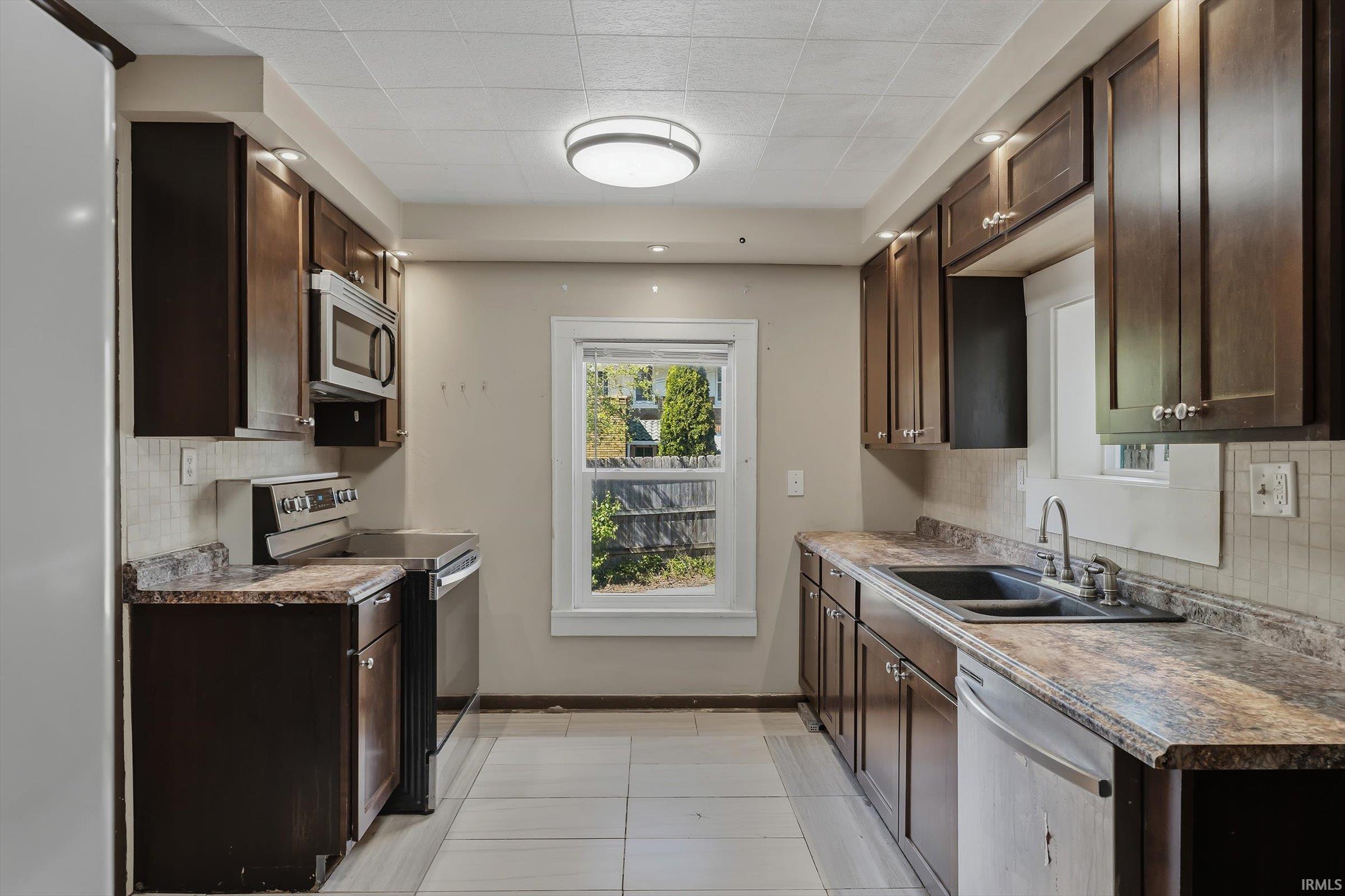 Kitchen featuring dark wood finish cabinetry, decorative backsplash, stainless steel appliances, and recessed lighting