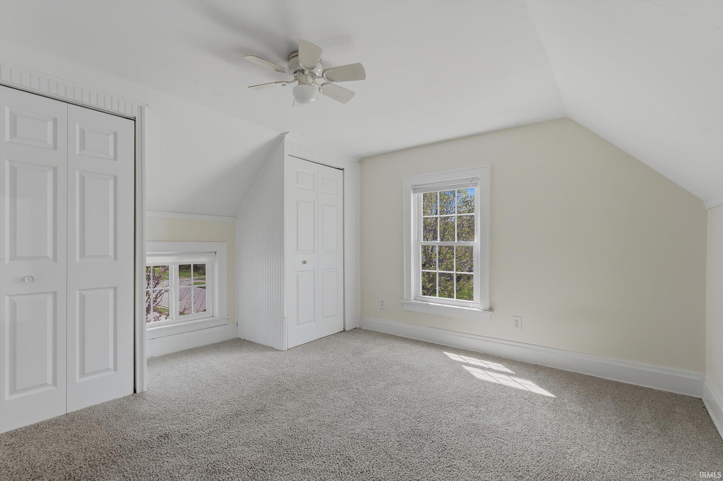 Bonus room featuring vaulted ceiling, ceiling fan, plenty of natural light, and light colored carpet