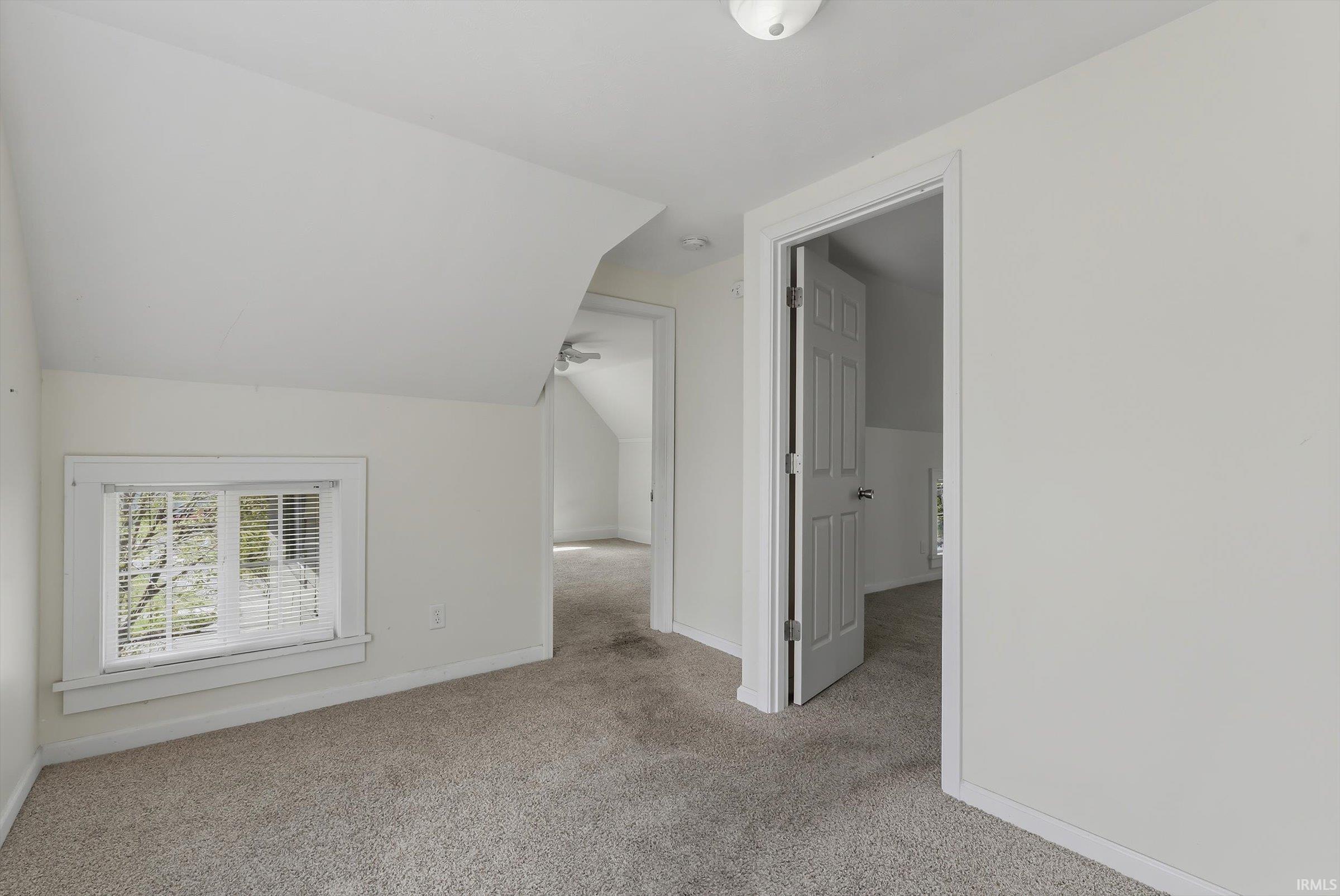 Additional living space with light carpet and lofted ceiling