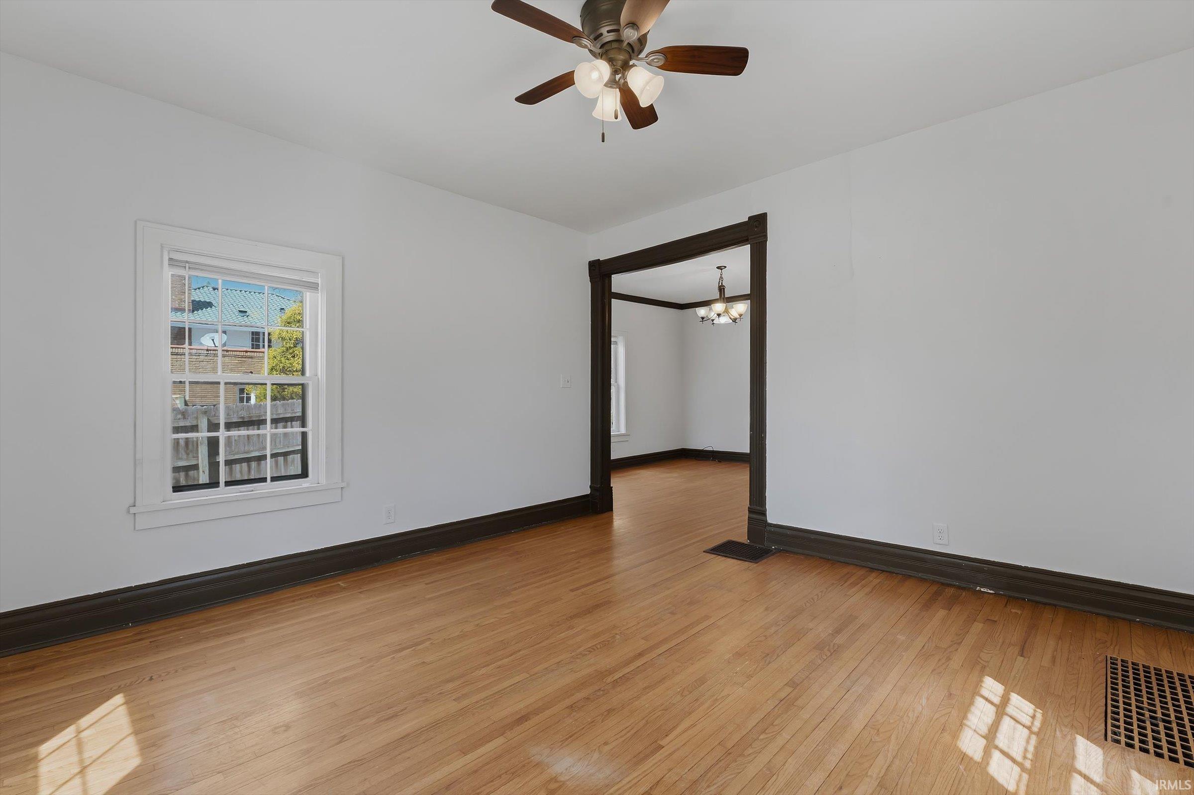 room featuring light wood finished floors, suspended lighting, and a ceiling fan