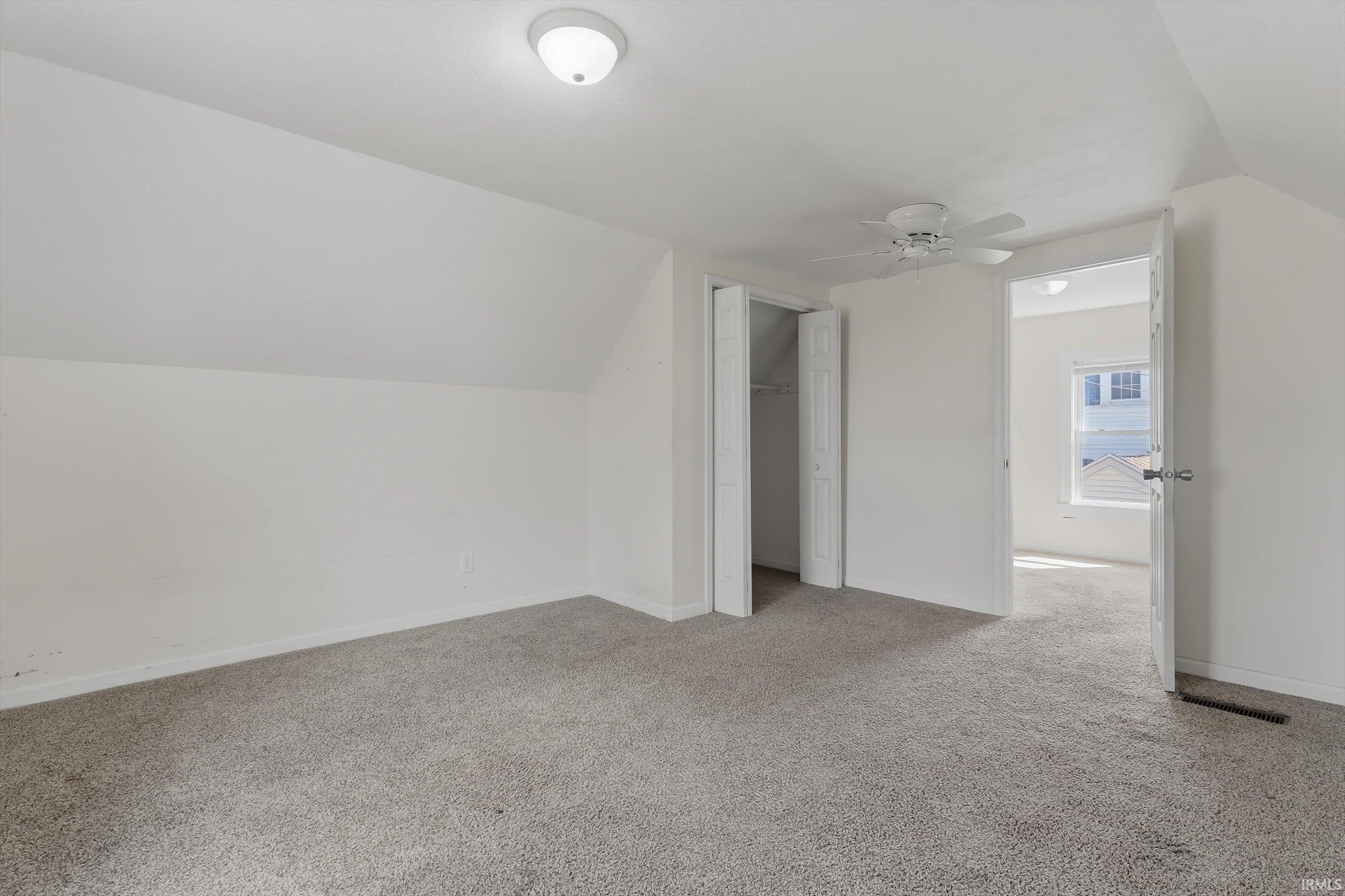 Bonus room with lofted ceiling, light colored carpet, and a ceiling fan