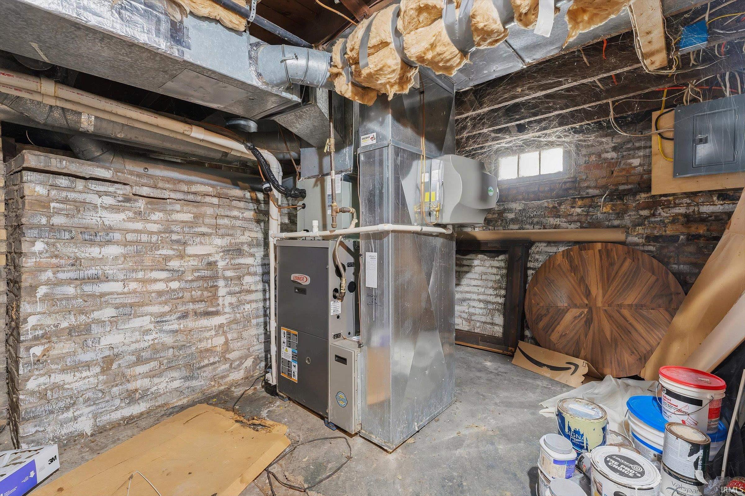 Utility room featuring electric panel and heating unit