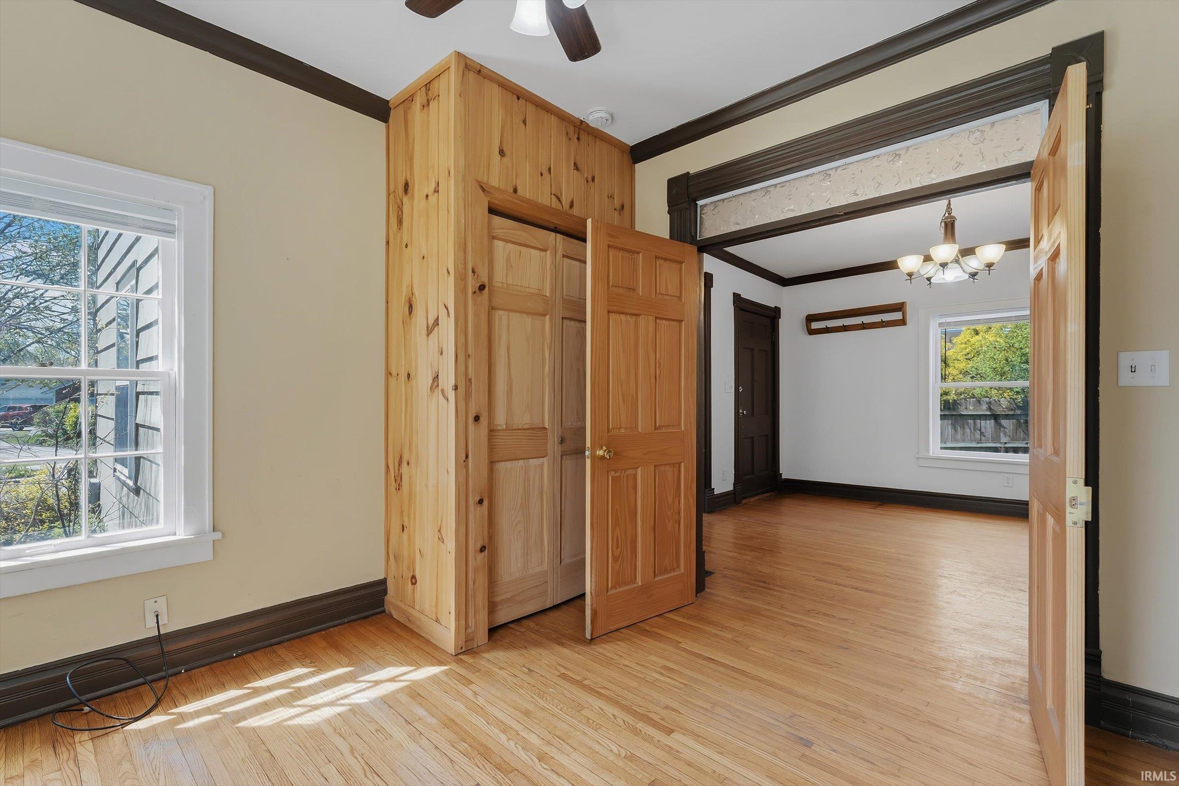 Spare room featuring light wood-type flooring, ornamental molding, a ceiling fan, and a chandelier