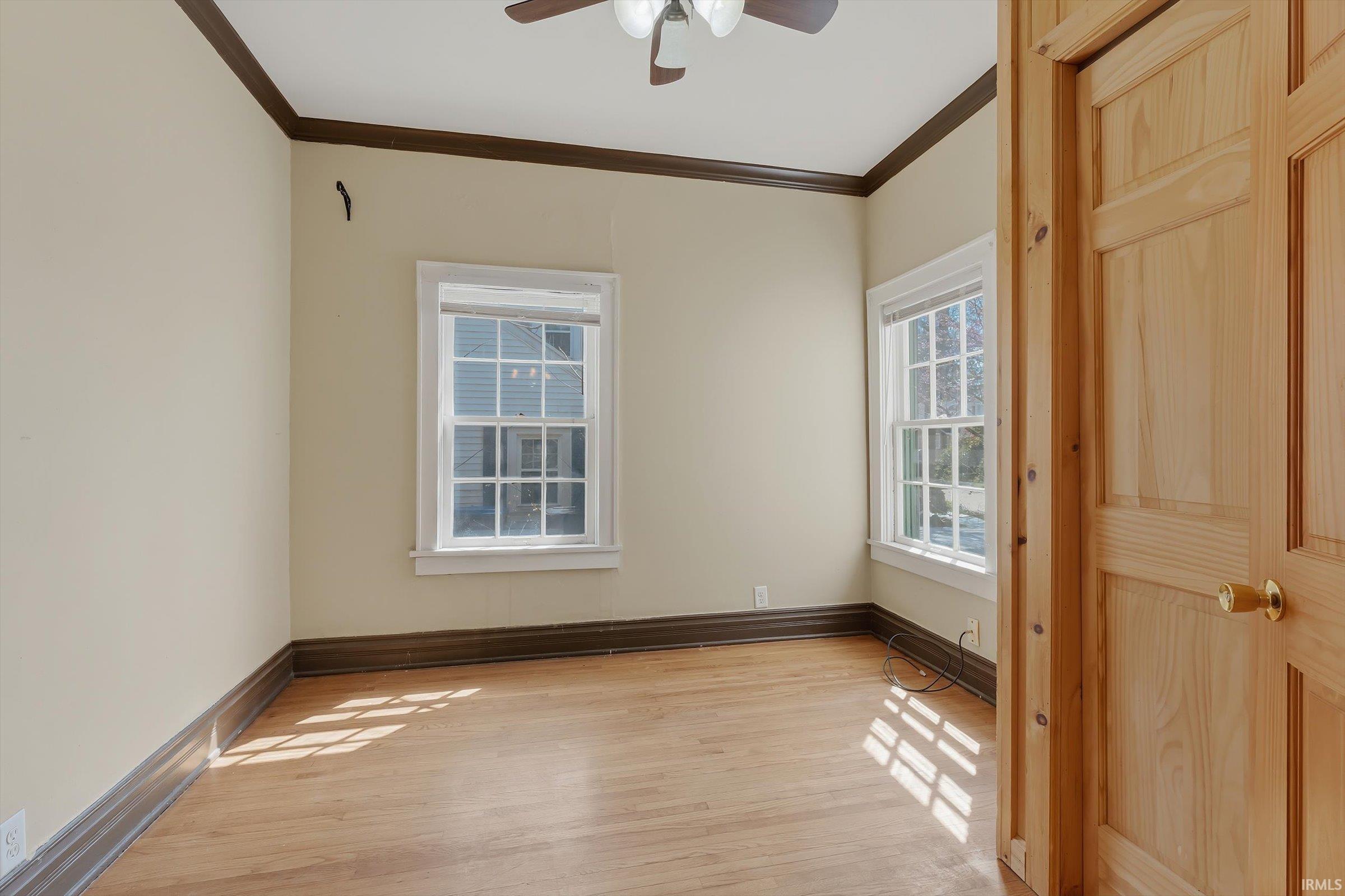 Spare room featuring crown molding, light wood-type flooring, and ceiling fan