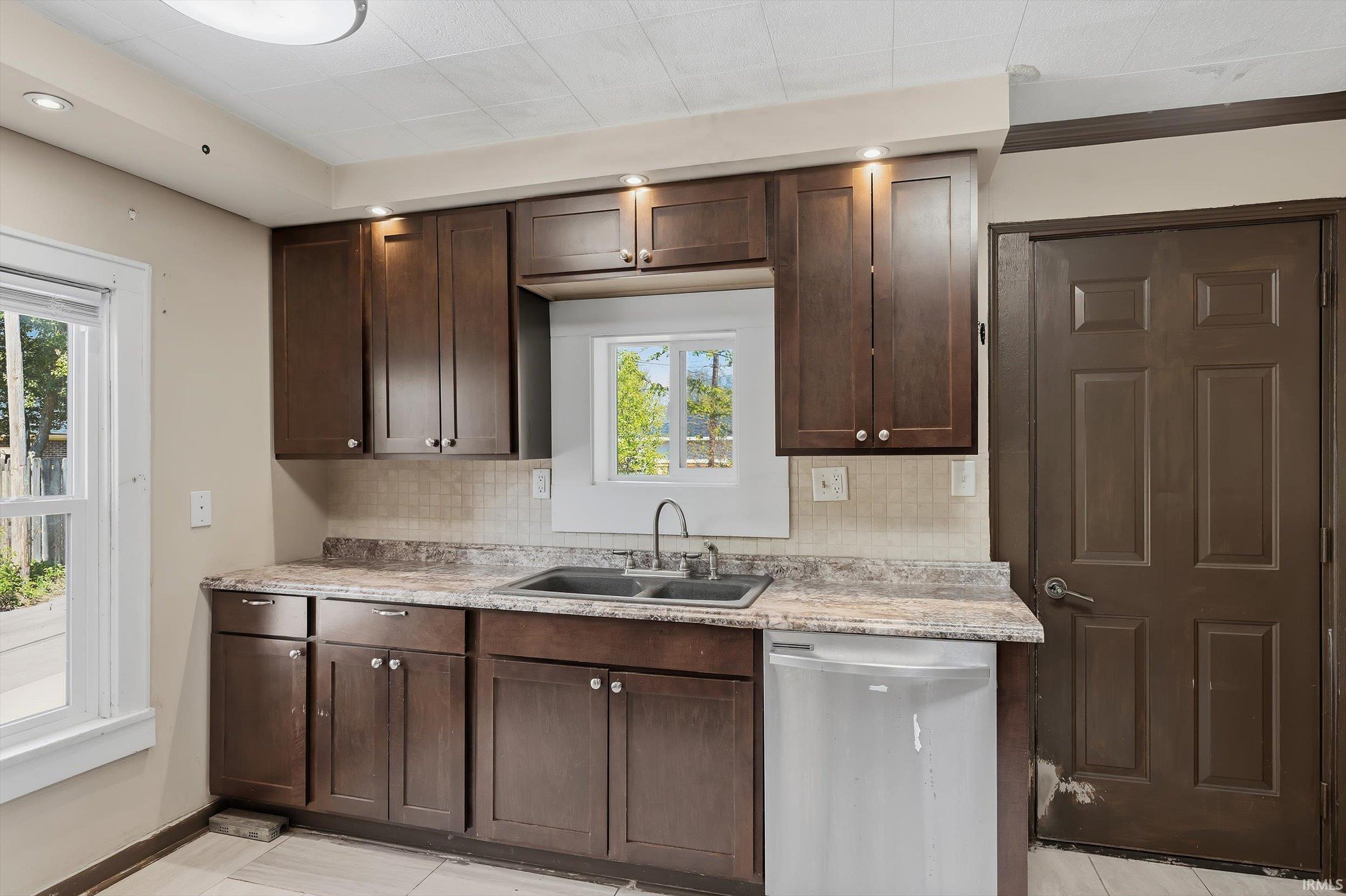 Kitchen with dark wood finish cabinets, stainless steel dishwasher, healthy amount of natural light, and recessed lighting