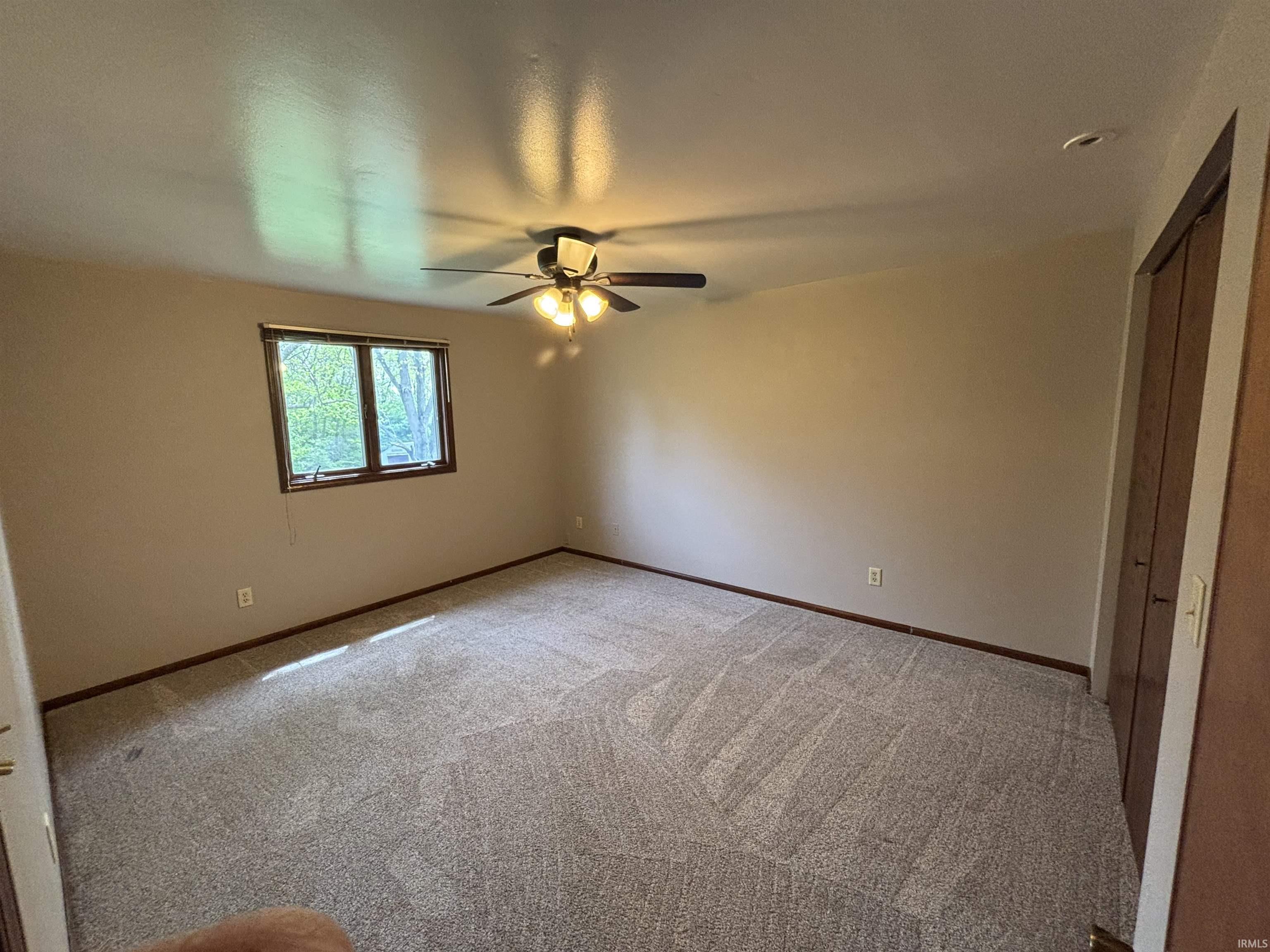 Unfurnished bedroom featuring a closet, light carpet, and a ceiling fan