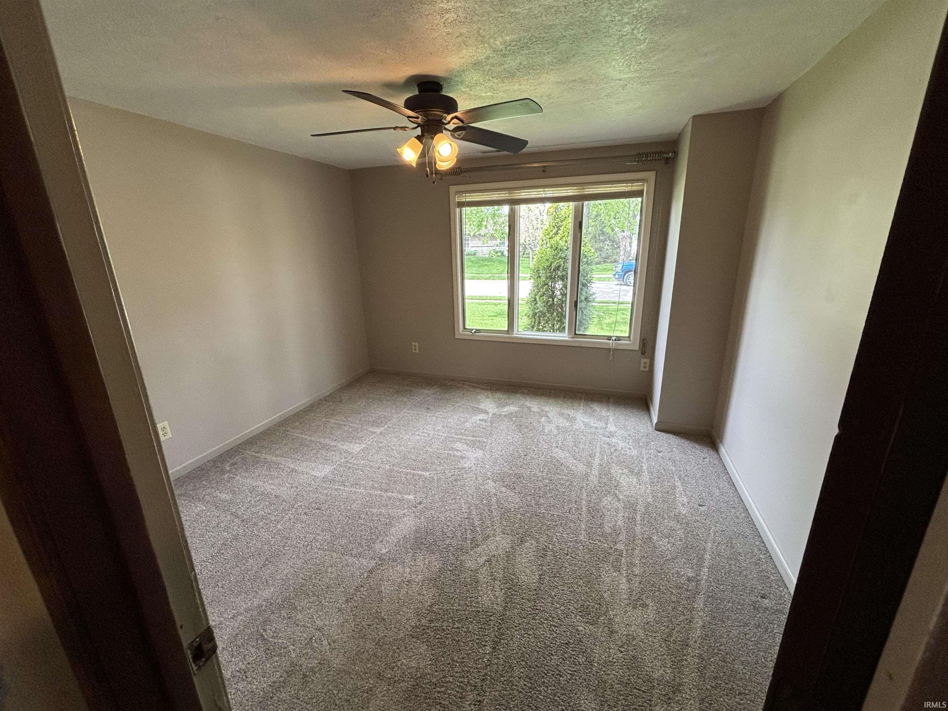 Spare room featuring a textured ceiling, light carpet, and ceiling fan