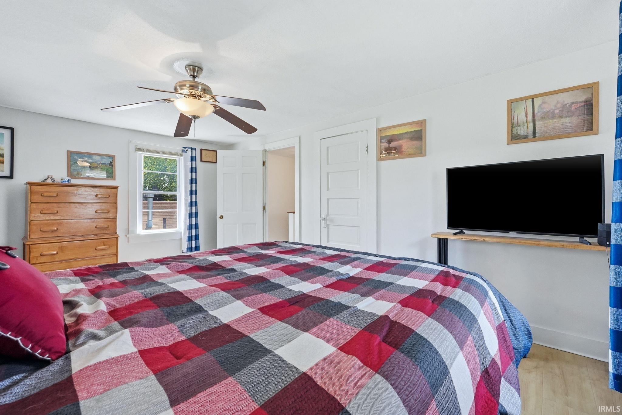 Bright bedroom featuring a ceiling fan, a window, and two paneled doors