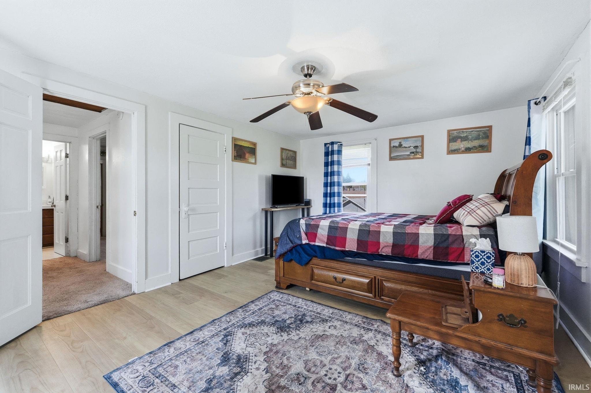 Bedroom featuring light wood-finish flooring, white trim, and a ceiling fan with integrated lighting