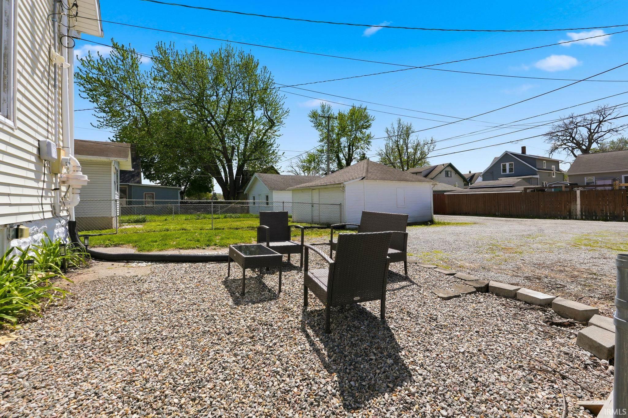 Gravel outdoor entertaining area with a retaining wall, a paved walkway, and a spacious lot